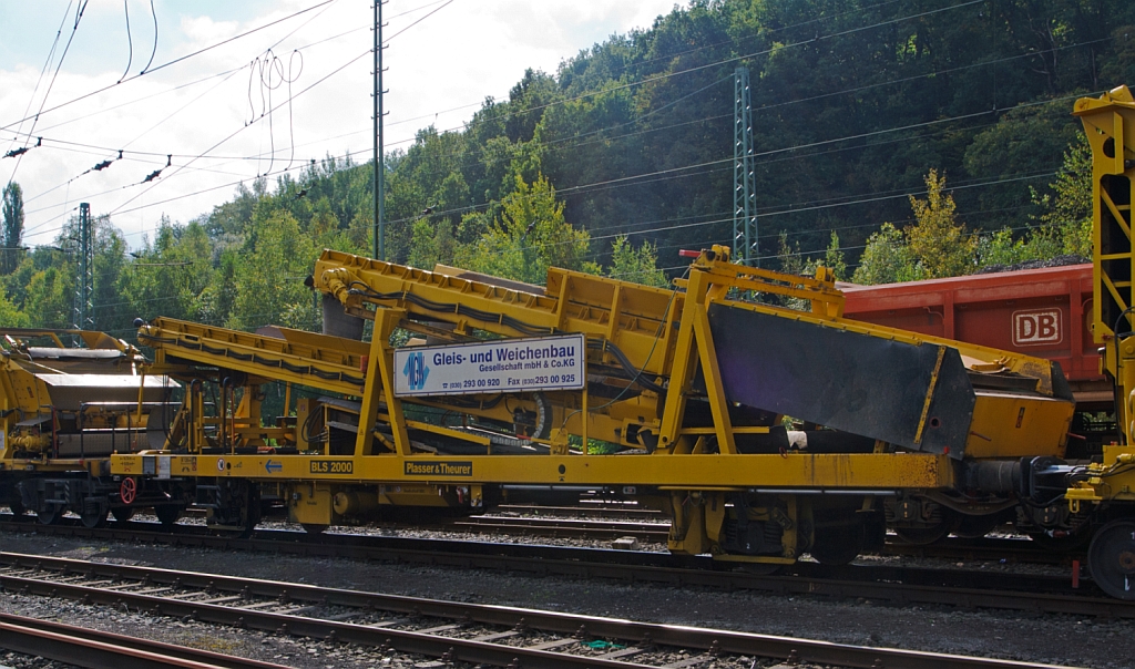 Plasser & Theurer Beladestation BLS 2000 gf (Schweres Nebenfahrzeug Nr. 97 19 26 903 57-8) der MGW Gleis- und Weichenbau (Berlin), abgestellt am 22.09.2012 in Betzdorf/Sieg.

Um Sch�ttg�ter mittels Erdbauger�ten (Bagger etc.) in MFS-Einheiten f�rdern zu k�nnen, ist die Beladestation entwickelt worden. Sie besteht aus Schottertrichter, eine festen breitem Kettenf�rderband und hydraulisch ein- und ausfahrbarem �bergabef�rderband mit Schwenkeinrichtung f�r die Arbeit im Gleisbogen. 

Die BLS 2000 ist ein zweiachsiges, gleisfahrbares Ger�t. 
Technische Daten:
Hersteller: Plasser & Theurer
Fabriknummer: 4063
Baujahr: 2003
Das Eigengewicht: 28 t
H�he: 	3.300 mm
Breite: 3.050 mm
Achszahl: 2
L�nge �ber Puffer: 14.740 mm (Mit Schottertichter und agefahrenem F�rderband entspr. l�nger)
H�chstgeschwindigkeit im Zugverband: 	100 km/h
Minimal befahrbarer Kurvenradius: 120 m
Die Energie f�r die Hydraulik liefert ein Dieselmotor, u.a. weden die F�rderb�nder hydraulisch angetrieben. 
Zur leichten Beladung kann der Schottertrichter w�hrend der Arbeit hydraulisch abgesenkt werden. Die Beladung kann auch durch Bagger oder Radlader erfolgen.