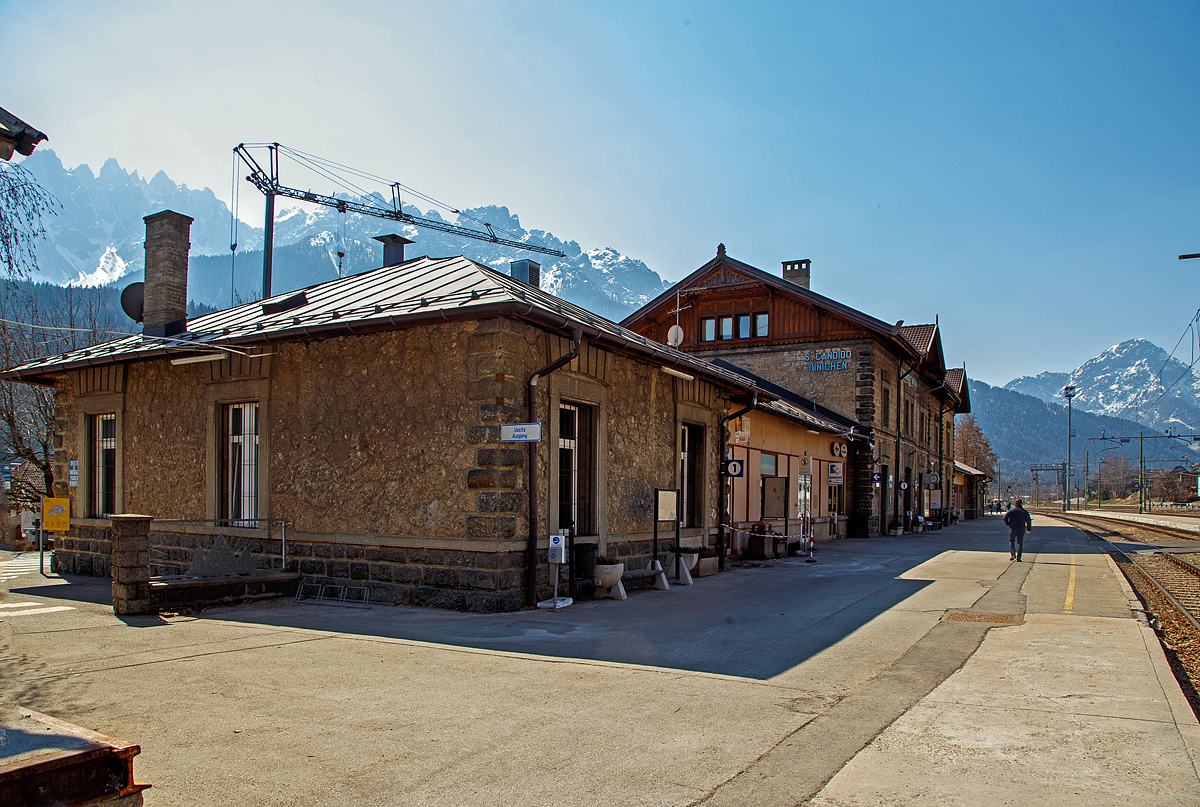Der Bahnhof Innichen / San Candido im Hochpustertal (im Osten Südtirols) am 27.03.2022, Blickrichtung Westen (Franzensfeste).

Der Bahnhof befindet sich auf 1178 m Höhe östlich vom Toblacher Sattel im Hochpustertal. Er liegt am westlichen Ortsrand von Innichen direkt an der SS 49. Die Entfernung zur Staatsgrenze zu Österreich im Osten beträgt etwa 7 km. So treffen hier die Pustertalbahn und die Drautalbahn im Osten Südtirols aufeinander. Er ist der Grenzbahnhof zwischen Süd- und Osttirol bzw. Italien und Österreich.

Der Bahnhof wurde 1871 zusammen mit den von der Südbahngesellschaft vorangetriebenen Strecken der Pustertalbahn und der Drautalbahn in Betrieb genommen. Zwischen 1985 und 1989 besorgten die FS - Ferrovie dello Stato die Elektrifizierung der Pustertalbahn von Innichen westwärts bis zum Bahnhof Franzensfeste mit Gleichstrom (3 kV), die Österreichischen Bundesbahnen hingegen die Elektrifizierung der Drautalbahn von Innichen ostwärts bis zum Bahnhof Lienz mit Einphasenwechselstrom (15 kV 16,7 Hz).

Betrieblich war der Bahnhof Innichen so ursprünglich als Zwischenbahnhof angelegt. Durch die Elektrifizierung der Drau- und Pustertalbahn mit unterschiedlichen Bahnstromsystemen in den 1980er Jahren wurde er jedoch faktisch zum doppelten Endbahnhof. Die Systemtrennstelle zwischen dem italienischen und österreichischen Netz konnte jahrelang nur von eigens erworbenen Korridorzügen der Reihe ÖBB 1822 ohne Lokwechsel passiert werden. Erst die Anschaffung von Mehrsystemtriebzügen der Baureihe Stadler Flirt (ETR 170) durch das Land Südtirol im Jahr 2013 ermöglichte wieder einen durchgehenden regionalen Bahnbetrieb zwischen Süd- und Osttirol.

Der Bahnhof Innichen wird von Regionalzügen der Trenitalia und der SAD bedient, die auch Busverbindungen zum Bahnhof betreibt. Diese fahren im Halbstundentakt abwechselnd bis Sillian bzw. Lienz in Osttirol (Österreich). Im Bahnhof Innichen findet neben dem Wechsel des Bahnstroms auch ein Personalwechsel zwischen SAD/Trenitalia und ÖBB statt.

Da der Bahnhof etwas abseits des Dorfkerns liegt, steht das Projekt einer Verlegung Richtung Osten näher zum Ortszentrum im Raum. 

Übrigens, die Drautalbahn, ist eine Ost-West-Eisenbahnverbindung entlang der Drau. Sie reicht von Maribor  (Marburg a. d. Drau, Anschluss an die alte Südbahn) bis Innichen, wo sie in die Pustertalbahn nach Franzensfeste übergeht. Sie nimmt somit im nördlichen Slowenien ihren Anfang, durchquert Kärnten und Osttirol und endet in Südtirol. 
