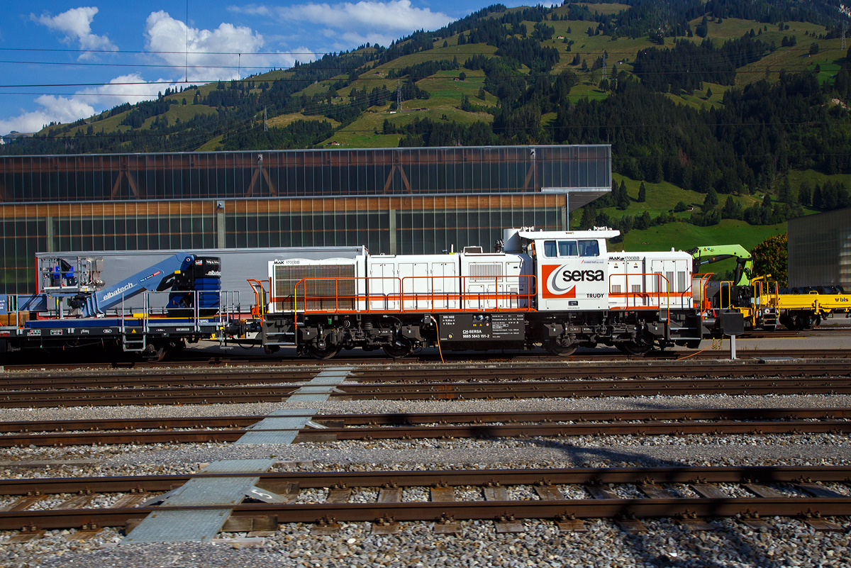 Die Am 843 151 „Trudy“ (98 85 5843 151-2 CH-SERSA) der Sersa (Rhomberg Sersa Rail Group), eine Schweizer Version der MaK G 1700-2 BB, ist am 08.09.2021 in Frutigen abgestellt (aufgenommen aus einem Zug).

Die Am 843 wurde 2004 von Vossloh in Kiel (ehem. MaK) unter der Fabriknummer 5001492 gebaut und an die Sersa AG (CH) geliefert. Die angeschriebene Bezeichnung „MaK G 1700 BB“ ist eigentlich nicht ganz richtig, denn die Schweizer Version Am 843 unterscheidet sich etwas von der MaK G 1700 BB.

Die Schweizerischen Bundesbahnen (SBB) bestellten bei Vossloh zunächst 59 Lokomotiven der Baureihe Am 843. Diese Lokomotiven werden im schweren Rangier- und leichten Streckendienst eingesetzt. Dazu gehört neben dem Rangierdienst in den größeren Rangierbahnhöfen und auf Stationen auch der Zustelldienst mit Streckenfahrten im Nahbereich. Ein weiteres Einsatzgebiet für die Lokomotiven besteht im Bau- und Interventionsdienst.

Um die Am 843 für diese sehr unterschiedlichen Aufgaben möglichst gut anzupassen fiel die Wahl auf eine der G1206 sehr ähnliche Maschinenanlage. Das Turbowendegetriebe L 5r4 z wurde in einer Version als Stufengetriebe verwendet. Es besetzt einen Rangiergang mit 40 km/h Höchstgeschwindigkeit und hohen Zugkräften im unteren Geschwindigkeitsbereich, sowie einen Streckengang mit 100 km/h Höchstgeschwindigkeit. Der Motor bleib dagegen der gleiche und leistet unverändert .1500 kW.

Für die übrigen Komponenten bediente man sich bei der Entwicklung der Am 843 jedoch der wesentlich jüngeren G 1700-2 BB, die den hohen Komfortwünschen der SBB gerecht wurden und deutlich mehr Einbauräume für diversen Sonderausrüstungen, z. B. die schweizerischen Zugsicherungen Integra Signum und ZUB 262 ct bietet. Trotzdem unterscheidet sich die Am 843 durch das Linksführerhaus und die für die Schweiz typischen eckigen Lampen und Geländer mit Schutzblechen schon äußerlich deutlich von ihr. Eine weitere Besonderheit ist der Partikelfilter zur Reduzierung des Rußausstoßes, die erstmals bei einer Lokmotive dieser Leistungsklasse in Serie eingebaut wurde.

Im Herbst 2003 begann die Lieferung die ersten Loks. Weitere Lokomotiven der Baureihe Am 843 konnten an andere Bahnen in der Schweiz verkauft werden. Zunächst erhielt das Bauunternehmen Sersa AG im Sommer 2004 drei Lokomotiven, die bei der Ausrüstung des Lötschberg-Basistunnels eingesetzt wurden. Für den gleichen Tunnel, jedoch für den Bau- und Interventionsdienst im regulären Betrieb erhielt die BLS zwei Jahre später ebenfalls drei Am 843. Als Besonderheit erhielten die BLS-Loks die europäische Zugsicherung ETCS, die im neuen Tunnel verwendet wird.

Der Lokrahmen besteht aus Walzträgern und massiven Blechen, welche in Schweißkonstruktion miteinander verbunden wurden. Dadurch entsteht ein stabiler und robuster Grundaufbau, welcher der Lok die notwendigen Festigkeiten verleiht. Im Lokrahmen wurde eine so genannte Umweltwanne montiert, welche aus dem Fahrmotor austretenden Flüssigkeiten (Mineralölen und Wasseremulsionen) auffängt, diese können mit Hilfe eines Ablasshahnes entleert und fachmännisch entsorgt werden.

Der vordere längere Vorbau beinhaltet neben dem Dieselmotor auch die notwendige Kühlanlage und das Antriebsgetriebe. Der kürzere hintere Vorbau enthält neben der Druckluftanlage auch die elektrischen Komponenten wie die Batterieladung.

Zwischen den beiden Vorbauten befindet sich das Mittelführerhaus, welches über die zwei diagonal gegenüberliegenden Eingangstüren betreten werden kann. In ihm sind alle für den Lokführer notwendigen Einbauten vorhanden. Ein Führersitz je Fahrpult und Fahrrichtung, welcher mit Arm- und Rückenlehnen ausgerüstet ist, erlaubt die sitzende Bedienung der Lokomotive. Dieser Führersitz ist drehbar gelagert und kann zusammengeklappt und unter den Führertisch verschoben werden. Dadurch ist auch die stehende Bedienung der Lokomotive ohne Behinderung möglich. Zur Entlastung der Füße sind auch verstellbare Fußstützen montiert. Der Fußboden ist mit einem Profilgummibelag belegt worden, der eine einfache Reinigung und dennoch einen guten Stand erlaubt.

Angetrieben wird die Lokomotive von einem 12-Zylinder-4Takt-Dieselmotor vom Typ Caterpillar 3512 B DI-TA-SCAC, dieser erbringt mit Hilfe der beiden Abgasturbolader und der Ladeluftkühlung eine maximale Leistung von 1.500 KW (2.040 PS). Seine höchste Drehzahl beträgt 1.800 U/min. Er wird mit Hilfe eines elektrischen Anlassers gestartet und ist elektronisch geregelt. Dadurch ist es möglich, den Motor bestmöglich im optimalen Leistungsbereich zu betreiben. Sein Gewicht beträgt mit 322 Liter Schmieröl und 134 Liter Kühlwasser 7.700 kg.

Die vom Dieselmotor erzeugte Leistung wird mittels einer Gelenkwelle auf das hydrodynamische Getriebe (Turbowendegetriebe), vom Typ Voith L5r4zseU2, übertragen. Das Getriebe hat eine maximale Leistung von 1.400 kW. Es beschränkt somit die Leistung der Lokomotive und verhindert zugleich, dass der Fahrmotor überlastet werden kann. Seine maximale Drehzahl ist gleich groß, wie jene des Fahrmotors.

Das Turbowendegetriebe besitzt für jede Fahrrichtung zwei Drehmomentwandler. Dem eigentlichen Wandlergetriebe ist eine mechanische Getriebe nachgeschaltet, das eine niedrige für den Rangierbetrieb bestimmte Schaltung und eine höhere für den Streckenbetrieb bestimmte Schaltung zur Verfügung zu stellen. Diese Umschaltung darf jedoch erst im Stillstand erfolgen.

Die Achsen in den Drehgestellen werden über Gelenkwellen vom Turbowendegetriebe angetrieben. Die Übertragung auf die Achsen erfolgt mit Hilfe von Stirnradgetrieben mit Kegelradvorgelege.

Technische Daten:
Gebaute Anzahl: 79
Spurweite: 1.435 mm (Normalspur)
Achsformel: B'B'
Länge über Puffer: 15.200 mm
Höhe: 4.220 mm
Breite: 3.080 mm
Drehzapfenabstand: 7.700 mm
Achsstand im Drehgestell: 2.400 mm
Dienstgewicht: 80 t
Höchstgeschwindigkeit: 100 km/h (40 km im Rangiergang)
Installierte Leistung: 1.500 kW (2.040 PS)
Anfahrzugkraft: 249 kN
Treibraddurchmesser: 1.000 mm
Motorentyp: Caterpillar 3512B DI-TA-SCAC
Nenndrehzahl: 1.800/min
Getriebe:  Voith Typ L 5r4 zseU2  
Kleinster bef. Halbmesser: 60 m
Tankinhalt: 3.500 l