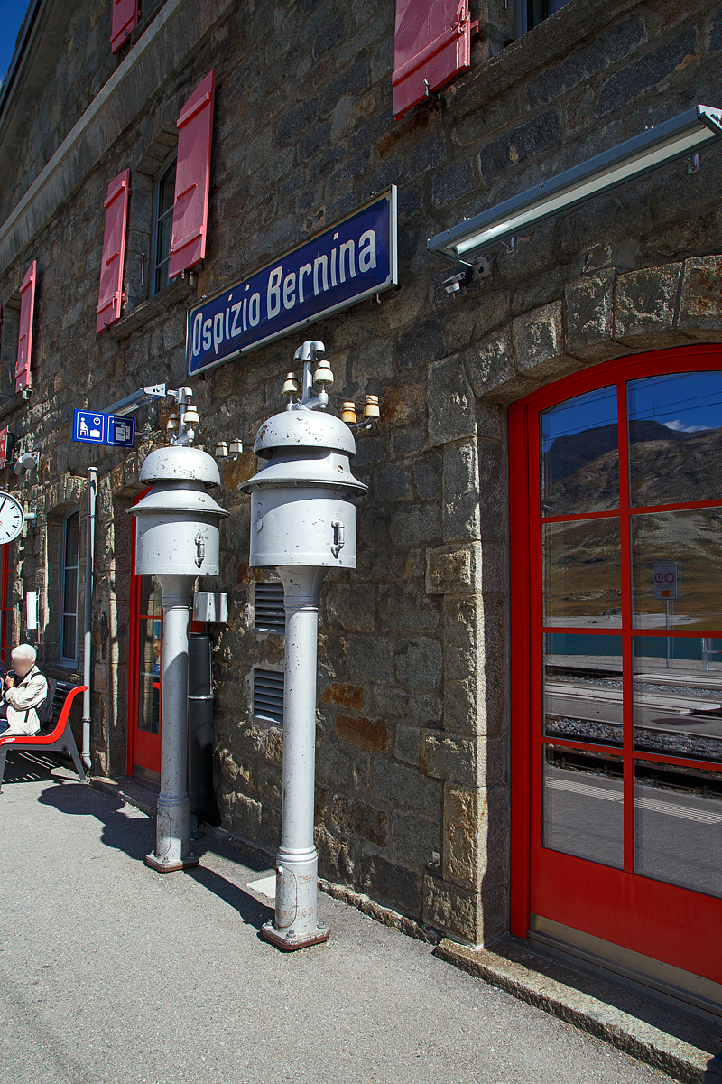Die beiden L�utewerke der Station Ospizio Bernina ist noch heute in Betrieb, sie k�ndigen das baldige ankommen der Z�ge an (06.09.2021), es sind Spindell�utwerke als Gruppenschl�ge.

In den fr�heren Jahren, als die Kommunikationsm�glichkeiten noch nicht in moderner Form vorhanden waren, kamen f�r die �bertagung von Informationen L�utwerke zum Einsatz. Diese signalisierten dem Bahnpersonal und den Reisenden mittels Hammerschl�gen an den Schallk�rper, welche Zugsverbindungen erwartet bzw. bei der Nachbarstation abgefahren oder fahrbereit sind. Im Jahre 1847 erfand die Berliner Firma Siemens & Halske das erste L�utewerk.

In der T�r der Station kann man auch den Lago Bianco und die Berniagruppe erkennen.