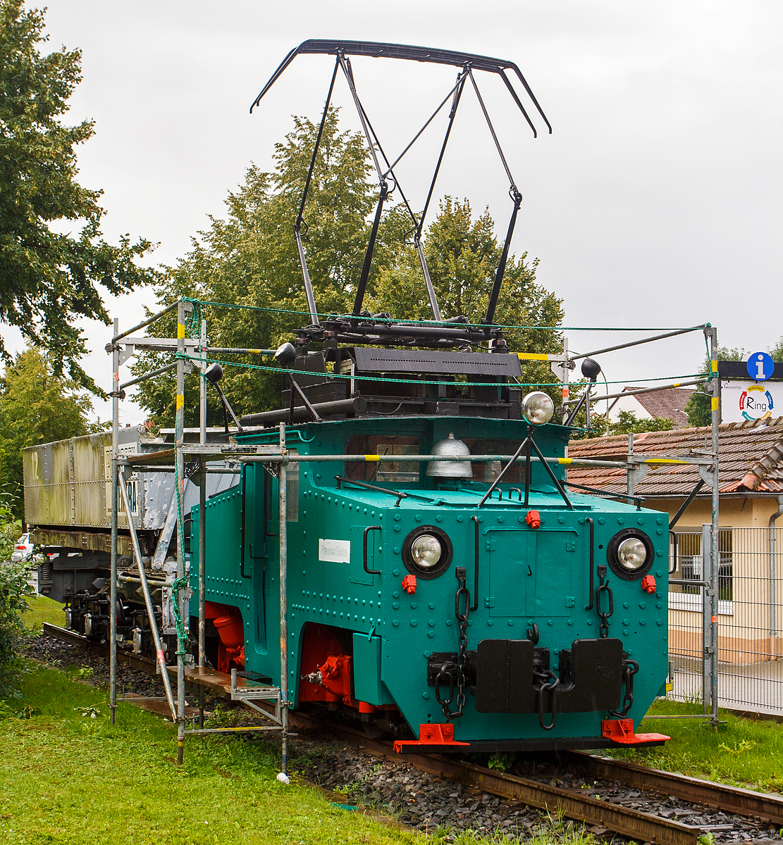 Die ehemalige E-Lok 5 der Preussen Elektra als Denkmal am 18.08.2014 in Wölfersheim-Södel. Leider zum Zeitpunkt der Aufnahme eingerüstet

Die Lok wurde 1924 von Henschel & Sohn in Kassel unter der Fabriknummer 20333 gebaut, die elektrische Ausrüstung ist von SSW. Die Ellok wurde an die Roddergrube AG in Brühl geliefert und als Rodder 1 bezeichnet. Mit der Übernahme durch die Rheinischen Braunkohlenwerke änderte sich die Betriebsnummer in RheinBraun 1055. Im Jahr 1964 erfolgte der Verkauf an die Preussische Elektrizitäts AG in Wölfersheim, wo die Lok nun unter der Nummer 5 bis 1992 für Aschezüge eingesetzt  wurde. Seit 1997 erinnert sie als Denkmal in Wölfersheim an die Bergbautradition.

Markant für diese Henschel E-Loks der Preussen Elektra für die Aschezüge sind die vier am Dach des Führerhauses angebrachten Scheinwerfer, die zur Weichensteuerung dienten.
 
TECHNISCHE DATEN:
Spurweite:  900 mm
Achsformel: Bo
Leistung:  172 kW (2x 86 kW)
Gewicht:  25 t
Höchstgeschwindigkeit: 45 km/h

In der Wetterau wurde bis 1991 Braunkohle, im Tief- und Tagebau abgebaut, ab 1913 wurde die Braunkohle auch zur Stromerzeugung verwendet. Ab den 1954 erfolgte die Stromerzeugung in einem größeren Umfang, so wurde auch die 900 mm Grubenbahn elektrifiziert (1200 V Gleichstrom).  Das Streckennetz wurde jeweils den Erfordernissen (Lage der Gruben) angepasst, die größte Streckenlänge war ca. 23 km.
Mit der Grubenbahn (im Volksmund  Kohlebähnchen  genannt) erfolgte der Transport der abgebauten Braunkohle von den Tagebaubetrieben zum Kraftwerk Wölfersheim einerseits. Aber auch die anfallende Asche im Kraftwerk Wölfersheim (ca. 1000 t pro Tag) musste weg und wurde mit der Grubenbahn vom Kraftwerk zu einem alten Tagebau bei Heuchelheim gefahren und dort abgekippt. 
Der Betreiber war die HEFRAG, später PreussenElektra (eine Tochter der VEBA AG), Konzernnachfolger ist heute die E.ON Energie.

Die Züge und Zugbetrieb
Die Kohlenzüge wurden gezogen von Krupp E-Loks und bestanden aus je sechs Sattelbodenwagen mit 28 bzw. 35 Kubikmetern Inhalt. Die Aschezüge (4 Wagen mit je 16 m³ Inhalt) wurden von (wie diese)  Henschel E-Loks gezogen. Insgesamt waren 35 Kohle- und 21 Aschewagen im Einsatz. Während die Krupp E-Loks 1954-1962 neu an die PREAG geliefert wurden, wurden die 1924 gebauten Henschel E-Loks gebraucht von der Roddergrube der Rheinischen Braunkohlenwerke ab1954 bezogen.

Der Kohlenverkehr lief in den späten Tagebaujahren in aller Regel nur an Vormittagen, während Aschezüge den ganzen Tag über fuhren. Ein Kohlenzug war mit rund 150 Tonnen Kohle beladen. Die Kohle wurde nach dem Entladen auf der Kohlemischhalde mit der Kohle aus anderen Tagebauen gemischt. Von dort wurde die Kohle anfangs über einen Schaufelradbagger, später über ein Haldenaufnahmegerät und Förderbänder zum Kraftwerk transportiert.

Die Weichen im Streckennetz der Grubenbahn wurden übrigens von den Lokomotiven aus über ein Lampensystem geschaltet, welches an jeder Lok angebracht war. Markant war dies vor allem bei den Loks der Aschezüge, da hier die Lampen aufgrund der kleineren Lokomotiven mit vier Auslegern am Führerhausdach angebracht waren.

