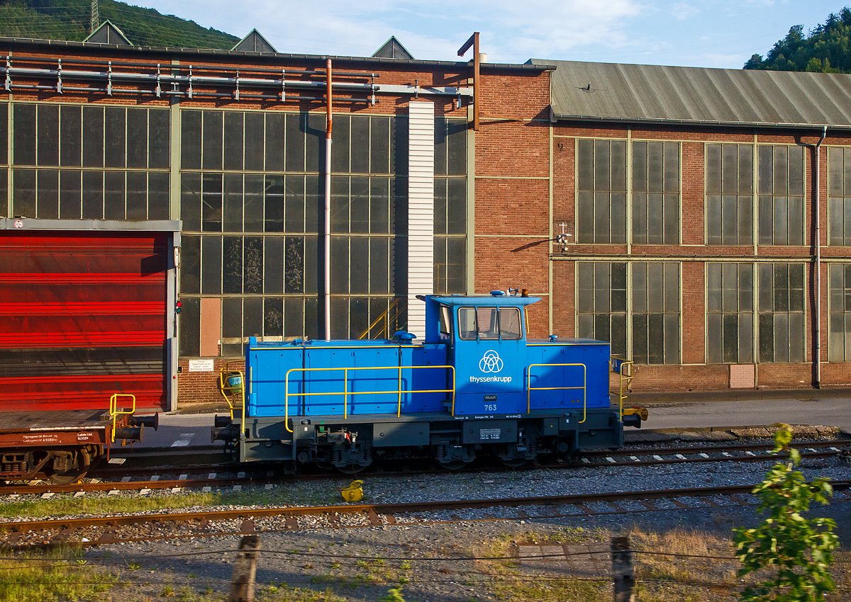 Die Lok 763 der thyssenkrupp Hohenlimburg GmbH, ex 763 Hoesch Hohenlimburg GmbH, ex SK 32 (Siegener Kreisbahn GmbH), am 31.05.2022 auf dem Werksgel�nde in Hagen-Hohenlimburg, aus einem fahrenden Zug heraus fotografiert.

Die Lok ist eine MaK G 763 C, sie wurde 1990 von der Maschinenbau Kiel GmbH (MaK) unter der Fabriknummer 700099 gebaut und an die damalige Siegener Kreisbahn GmbH als SK 32 geliefert. Zum 23.12.2004 nach der Umbenennung zur Kreisbahn Siegen-Wittgenstein GmbH wurde sie zur KSW 32 und war von 2005 bis 2007 an die MEG - M�rkische Eisenbahn-Gesellschaft mbH in L�denscheid vermietet. Im Dezember 2007 ging sie �ber Vossloh Locomotives an die Hoesch Hohenlimburg GmbH als Lok 763, zum 01.07.2016 wurde Hoesch von thyssenkrupp �bernommen.
