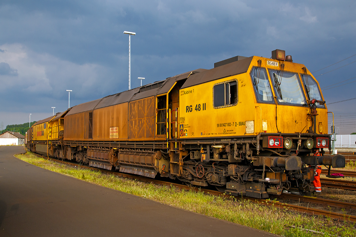 
Die LORAM Schienenschleifmaschine RG 48 II, Schweres Nebenfahrzeug Nr. 99 80 9427 002-7 D-SAUB, der Schweerbau abgestellt am 24.05.2015 beim ICE-Bahnhof Montabaur.

Die Schienenschleifmaschine RG 48 besteht aus drei Wagenteilen, zwei Schleifwagen (1+2) und eine Arbeitswagen dazwischen. Jeder Wagen hat zwei Drehgestelle mit zwei Achsen. Die Schleifwagen haben insgesamt 48 Schleifmodule (24 pro Wagen), die elektrisch verstellt werden können, der Anpressdruck geschieht hydraulisch. Die Schleifmotoren haben eine Leistung von jeweils 22,4 kW. Unter dem Arbeitswagen befindet sich ein Wassertank, mit einem Fassungsvermögen von 18.927 Liter (5.000 Gallon), für Kühl- und Löschwasser. Die Maschinen kann in beide Richtungen arbeiten. Der kleinste bearbeitbare Bogenradius beträgt 180 m. Die Arbeitsgeschwindigkeit ist zwischen 2 und 15 km/h stufenlos einstellbar und abhängig vom Materialabtrag, vorzugweise wir zwischen 8 und 12 km/h gearbeitet. Bei einer Schleifgeschwindigkeit von 8 km/h können 0,25 mm Material angetragen werden. Für das Schleifen des gesamten Schienenkopfes beträgt die Stundenleistung zwischen 700 und 1400 m Gleis.

Hersteller dieser Maschine ist Loram Maintenance of Way, Inc. aus Minnesota (USA).

Technische Daten:
Spurweite: 1.435 mm
Anzahl der Achsen: 12 (in 6 Drehgestellen)
Länge über Puffer: 62.043 mm (3 x 20.810 mm)
Drehzapfenabstände: 13.110 mm
Achsabstände in den Drehgestellen: 1.800 mm
Raddurchmesser: 920 mm
Eigengewicht: 245.000 kg
Achslast: 21,5 t
Zul. Anhängelast: 40 t
Zur Mitfahrt zugel. Personen: 6
Höchstgeschwindigkeit: 100 km/h
Kleinster befahrbarer Gleisbogen: R 150 m
Zugelassen für Streckenklasse: D2 und höher