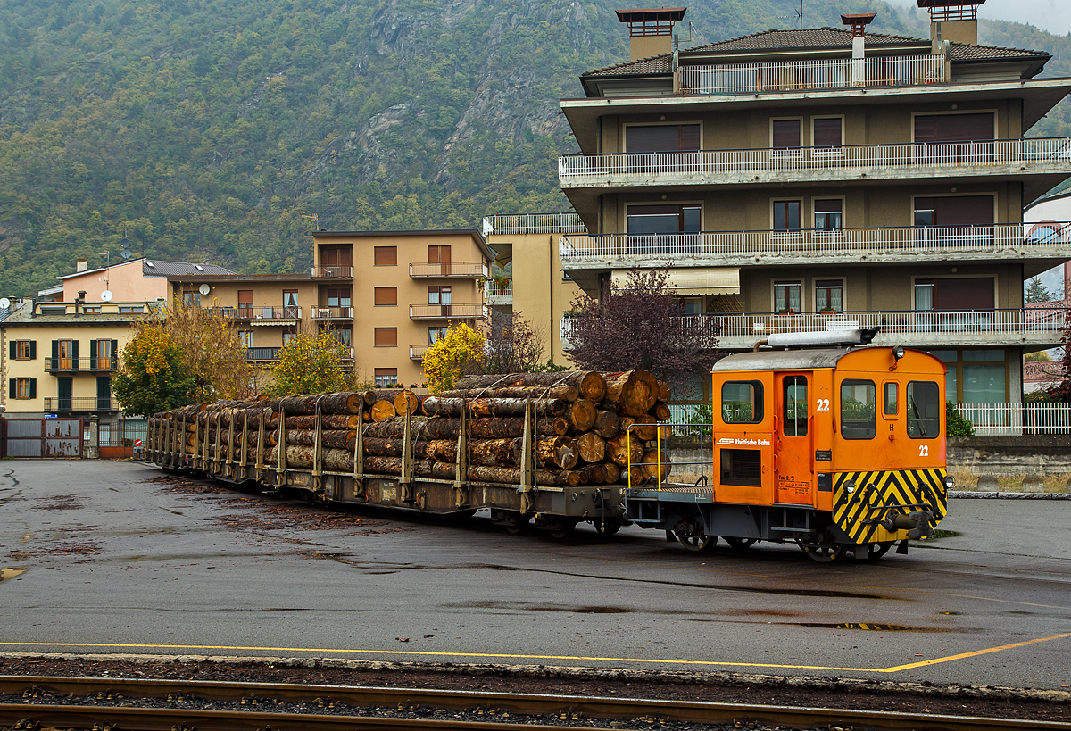 Die RhB Tm 2/2 22, ex RhB Tm 2/2 58, steht am 02.11.2019 mit drei angehangenen und mit Rundholz beladenen Flachwagen vom Typ “Sp-w“ der Serie 8271 – 8300 beim Bahnhof Tirano. 

Der Traktor vom Typ RACO 55 LA 4 wurde 1965 von RACO (Robert Aebi AG) unter der Fabriknummer 1717 gebaut. Im Jahr 1989 erfolgte die Remotorisierung mit einem Cummins Motor vom Typ 4BT 3.9 und die Umzeichnung in Tm 2/2 22.

Als Tm 2/2 werden diesel- oder benzinbetriebene Traktoren (Kleinlokomotiven) bezeichnet.
Die RhB besa� im Laufe der Jahre insgesamt 42 zweiachsige Traktoren mit Verbrennungsmotoren. Davon haben sechs eine Funkfernsteuerung und tragen deshalb die Bezeichnung Tmf 2/2. Die verbleibenden 36 Fahrzeuge teilen sich auf in 26 heute orange Rangierfahrzeuge und 10 heute gelbe Baudiensttraktoren. Insgesamt hatte die RhB 12 dieser baugleichen RACO 55 LA 4.

Zwischen 1957 und 1969 lieferte die Firma Robert Aebi (Raco) die dieselmechanischen Traktoren Tm 2/2 64–67, 62–63, 57–61 und schlie�lich noch Nummer 56. Die Nummerierung erfolgte vor den schon vorhandenen Tm 68 und 69. Basis f�r diese Fahrzeuge waren die Tm II der SBB. Der mechanische Aufbau wurde von RACO entwickelt und gebaut, der Dieselmotor war von Saurer-SLM. Die Kraft�bertragung vom Motor auf die Achsen erfolgte mittels Kettenantrieb, dadurch sind diese Traktoren nur f�r den leichten Verschubdienst an Bahnh�fen geeignet. Bei einem Umbau in den Jahren 1989-90 wurden die Motoren von SLM durch solche von Cummins ausgetauscht, dabei wurden die Nummern auf 15 bis 26 ge�ndert und die Traktoren dabei in die Ablieferungsreihenfolge gebracht. Die urspr�nglich rotbraun, heute orange lackierten Fahrzeuge sind 5,06 m lang und 9 t schwer. Sie bestreiten den Rangierdienst auf Stationen mit kleinem bis mittlerem G�teraufkommen, wobei die meisten der 12 Traktoren ihrer jeweiligen �Heimatstation� fest zugeteilt sind.

TECHNISCHE DATEN:
Spurweite: 1.000 mm
Achsfolge: B
L�nge �ber Puffer: 5.060 mm
Breite: 2.640 mm
Leergewicht: 9 t
Ladegewicht: 2 t
H�chstgeschwindigkeit: 30 km/h (55 km/h Schleppfahrt)
Motorbauart: 4-Zylinder-Dieselmotor
Motortyp: ab 1989/90 Cummins 4BT 3.9 (urspr�nglich Saurer-SLM 4 VD 11)
Motorleistung: 62 kW (urspr�nglich 44 kW)
Anfahrzugkraft: 30 kN (urspr�nglich 25 kN)
Stundenzugkraft: 15 kN bei 10 km/h
Leistungs�bertragung: Rollenkette

Die offenen, vierachsigen RhB Flachwagen mit Rungen vom Typ Sp-w der Serie 8271 – 8300 sind die Allrounder der Rh�tischen Bahn schlechthin und werden vorwiegend f�r den Transport von Rundholz eingesetzt. An jeder L�ngsseite besitzen sie sechs Steckrungen.

TECHNISCHE DATEN vom Typ Sp-w (8271 bis 8300) :
Typenbezeichnung:  Sp-w
Wagennummern:  8271 bis 8300
Baujahr: 1979
Spurweite: 1.000 mm
L�nge �ber Puffer: 16.540 mm 
Drehzapfenabstand: 11.000 mm 
Achsabstand im Drehgestell: 1.400 mm
Laufraddurchmesser: 750 mm (neu)
Breite �ber Alles: 2.700 mm
Ladel�nge: 15.500 mm
Ladebreite:  2.310 mm
Rungenh�he: 1.050 mm
Ladefl�che: 34 m�
Eigengewicht:  ca. 15.600 kg
Ladegewicht:  33 Tonnen
H�he ab Schienenoberkante: 965 mm