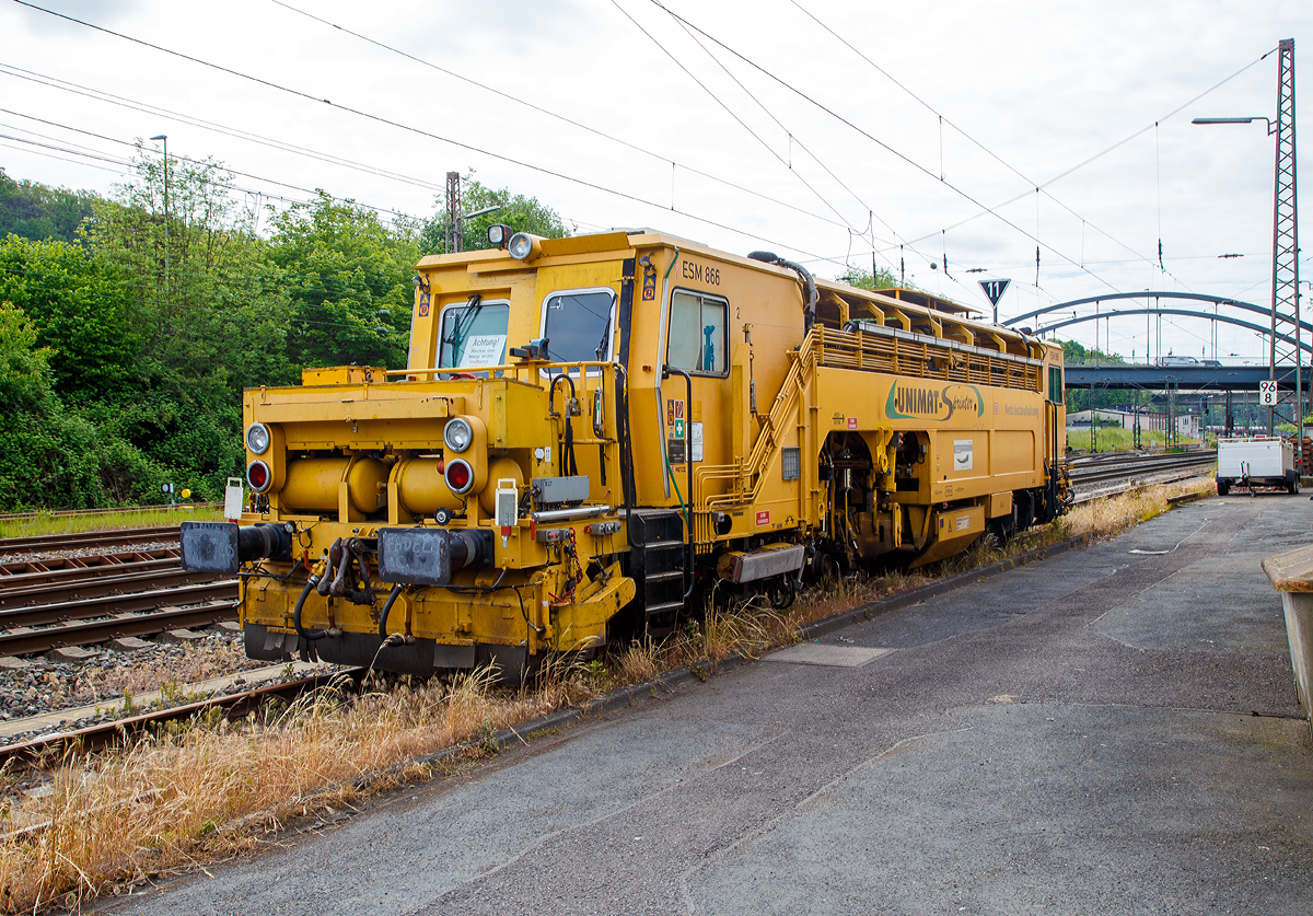 
Die Universal-Stopfmaschine Unimat-Sprinter ESM 866 der DB Netz AG (Schweres Nebenfahrzeug Nr. 97 43 52 006 17-1) steht am 31.05.2019 in Kreuztal. Der Unimat-Sprinter ist eine von Plasser und Theurer entwickelte Stopfmaschine f�r Gleise, Weichen und Kreuzungen, speziell konzipiert f�r die rasche und pr�zise Behebung von Einzelfehlern. Daher auch die Abk�rzung ESM = EinzelfehlerStopfMaschine.

Die Stopfmaschine (ESM – 08 – 275 / Sprinter) wurde 2000 von Plasser & Theurer unter der Fabriknummer 1169 gebaut und an die DB Netz AG geliefert.

Die typische L�nge eines Einzelfehlers betr�gt 9 bis 15 Schwellen, er kann sich in Einzelf�llen aber bis zu 100 m weit erstrecken. Die Ursachen liegen nicht im direkten  Zusammenhang  mit  Nivellier-  und  Richtarbeiten oder Zugbelastungen, sondern vielmehr in punktuellen, scharf   abgegrenzten Schw�chen im Unterbau, Frostsch�den usw.
Da dieser Einzelfehler in einem v�llig intakten Abschnitt liegt,  der keiner durchgehenden Behandlung bedarf, ist es viel zu aufwendig, solche Abschnitte zur G�nze zu bearbeiten. Die Behebung eines Einzelfehlers ist aber unumg�nglich, da nicht  nur Gr�nde wie kostspielige Langsamfahrstellen daf�r sprechen, sondern auch die Sicherheit des Fahrweges garantiert werden muss.

Der UNIMAT SPRINTER ist eine speziell f�r die Einzelfehlerbehebung entwickelte Stopfmaschine. Sie ist mit zwei Weichenstopfaggregaten mit jeweils vier Schwenkpickeln zur universellen Bearbeitung von Strecken und Weichen  ausgestattet. Das kombinierte Hebe- und Richtaggregat besteht aus einem Hebehaken, einer Richtrolle und einer Rollhebezange pro Schienenstrang. F�r eine schnelle �berstellung zur Baustelle ist die Maschine mit einem hydrodynamischen Antrieb f�r eine H�chstgeschwindigkeit von 100 km/h ausgelegt. Flankenpfl�ge, die im Bereich des vorderen Drehgestells montiert sind und eine Kehrb�rste am hinteren Ende der Maschine, sorgen nach den Stopfarbeiten f�r  die Herstellung des geforderten Schotterprofils.

Technische Daten der UNIMAT SPRINTER:
Spurweite: 1.435 mm
Achsanzahl: 4 (in 2 Drehgestellen)
Achsabstand im Drehgestell: 1.500 mm
Lauf- und Treibraddurchmesser: 730 mm (neu)
Drehzapfenabstand: 10.500 mm
L�nge �ber Puffer: 18.140 mm
Eigengewicht: 54t
Anh�ngelast: 40 t
H�chstgeschwindigkeit: 100 km/h
Zugelassen zur Mitfahrt: 4 Pers.
Kleinster befahrbarer Kurvenradius:  R 90 m      
Zugelassen f�r Streckenklasse: A und h�her