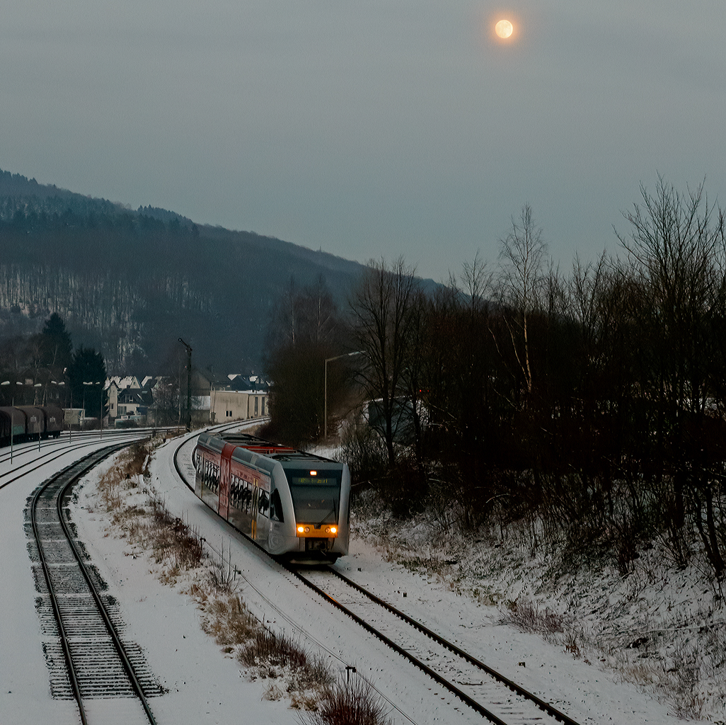 
Einen Tag später der gleicher Stelle der gleiche Triebwagen und Verbindung, nur mit fast vollen Mond...
Der HLB 127 bzw. VT 526 127  (95 80 0646 427-4 D-HEB / 95 80 0946 927-0 D-HEB / 95 80 0946 427-1 D-HEB) ein  Stadler GTW 2/6 der HLB (Hessische Landesbahn GmbH) fährt am 21.01.2016, als RB 96  Hellertalbahn   (HLB 61778) die Verbindung Dillenburg - Haiger - Neunkirchen - Herdorf - Betzdorf), hier erreicht er nun bald den Bahnhof Herdorf. 
Einen Gruß an den netten TF zurück.