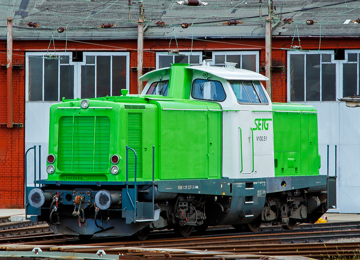 Im neuen grün-weißen Outfit der SETG....
Die SETG V100.51 alias  211 237-3 (92 80 1211 237-3 D-SRA) der Salzburger Eisenbahn TransportLogistik GmbH, ex DB 211 237-3, ex DB V 100 1237, steht am 22.06.2019 vor dem Siegener Ringlokschuppen. Hier bei Rail-Design Bäcker hat sie vor kurzem ihre neue Lackierung bekommen, wie immer ist sie sehr gut gelungen.
Eigentlich steht die Lok auch in ihrer alten Heimat, denn sie war bei der DB dem BW Siegen zugeordnet.
Viele Quellen  schreiben als NVR-Kennung D-SETG, aber angeschrieben ist D-SRA für S-Rail GmbH (Freilassing) ein Tochterunternehmen Salzburger Eisenbahn TransportLogistik GmbH.

Im März 2019 konnte ich sie noch in Hamburg in northrail Outfit fotografieren, siehe https://hellertal.startbilder.de/bild/Deutschland~Unternehmen~Northrail/656611/die-northrail-211-237-3-92-80.html

Die V 100.10 (West) wurde 1961 von Krupp unter der Fabriknummer 4347 	gebaut und als V 100 1237 an die Deutsche Bundesbahn geliefert, zum 01.01.1968 	erfolgte die Umzeichnung in 211 237-3 und bereits 1987 die Ausmusterung bei der DB. 1990 ging sie über On Rail Gesellschaft für Eisenbahnausrüstung und Zubehör mbH an die Solvay Österreich GmbH, Werk Ebensee (A)  als 211 237-3 „Didi 1“.
2010 kam sie wieder nach Deutschland zur northrail GmbH in Kiel als Mietlok bis sie Ende 2018 an die SETG verkauft wurde.

Die BR 211 (V100.10)
Die Baureihe V 100 ist ein von der Deutschen Bundesbahn (DB) Ende der 1950er Jahre beschaffter Lokomotivtyp mit dieselhydraulischem Antrieb, der auf nicht elektrifizierten Nebenbahnen die dort verwendeten Dampflokbaureihen ersetzen sollte. Die Baureihe V 100 wurde in mehreren verschiedenen Ausführungen produziert. Die Baureihe V 100.10 (BR 211) sollte im leichten Reise- und Güterzugdienst auf Nebenstrecken eingesetzt werden. Dieser Loktyp wurde 1956 von dem Bundesbahn-Zentralamt München zusammen mit der MaK für die DB entwickelt.

Die Lokomotiven der V-100-Familie haben zwei Drehgestelle mit je zwei angetriebenen Radsätzen. Als Motoren wurden in den Ursprungsausführungen schnelllaufende Zwölfzylinder-V-Motoren von Maybach, Mercedes-Benz oder MAN verwendet. Die Kraftübertragung vom Motor auf die Radsätze erfolgt über ein hydrodynamisches Getriebe mit zwei Drehmomentwandlern und einer Strömungskupplung und nachgeschaltetem mechanischem Zweigang- und Wendegetriebe über Gelenkwellen auf die einzelnen Radsatzvorgelege in den Drehgestellen. Die Drehgestelle haben einen geschweißten H-förmigen Rahmen mit zwei Längs- und zwei Querträgern. Auf den Drehgestellen stützt sich der aus gewalzten Stahlprofilen und Blechen ebenfalls als Schweißkonstruktion gefertigte Lokomotivrahmen ab. Zur Dämpfung der Drehbewegungen der Drehgestelle gegenüber dem Lokrahmen sind beiderseits der Drehzapfen Stoßdämpfer angeordnet.

Im Spätherbst 1958 wurden die ersten sechs Erprobungsmaschinen ausgeliefert. Die als V 100 001 bis 005 eingereihten Loks wurden mit einem 809 kW (1.100 PS) starken Motor ausgerüstet. Die V 100 006 erhielt jedoch einen Motor mit 993 kW (1.350 PS) Leistung. Die letztgenannte Lokomotive bildete die Grundlage für die V 100.20, die spätere Baureihe 212. Die V 100 007 wurde als siebte Erprobungslok von der Maschinenbau Kiel (MaK) zunächst auf eigene Rechnung gebaut. Sie war die erstgebaute V 100 überhaupt und stand dem BZA München bereits vier Monate vor Ablieferung der restlichen Erprobungsloks für Versuchsfahrten zur Verfügung. 

Erste Wahl für eine Lokomotive in der Leistungsklasse bis 1.100 PS wäre das bewährte hydraulische Dreiwandler-Getriebe LT306r aus der V 200.0 gewesen. Dieses Getriebe entsprach allerdings nicht mehr dem neuesten technischen Stand und bot keine Reserven zur Steigerung der Eingangsleistung über 1.100 PS hinaus. Die DB ließ deshalb von Voith ein neues Getriebe L216rs in Wandler-Wandler-Kupplung-Ausführung entwickeln. Durch Verringerung der Übersetzung zwischen Getriebeeingangswelle und Hohlwelle ließ sich das Getriebe an höhere Motorleistungen anpassen. Dies wurde später für die Baureihe 212 genutzt. Das Getriebe ist als Einwellen-Getriebe konstruiert, das heißt die Pumpenräder laufen auf einer Hohlwelle, in der die Sekundärwelle mit den Turbinenrädern liegt. Die Leiträder sind feststehend mit dem Getriebegehäuse verbunden. An den hydraulischen Teil schließt sich das mechanische Nachschaltgetriebe an, bestehend aus Wende- und Stufenschaltung. 

1961 begann man dann mit der Serienlieferung, die bis 1963 andauerte. Neben MaK wurden die Loks auch von Deutz, der Maschinenfabrik Esslingen, Henschel, Jung, Krauss-Maffei und Krupp gefertigt.

In den Serienlokomotiven kamen überwiegend Motoren von Maybach und Mercedes-Benz zum Einsatz. Die in geringen Stückzahlen beschafften Motoren von MAN waren bis spätestens 1980 vollständig ersetzt. 

Im Rahmen der Umnummerierung der Triebfahrzeuge der Deutschen Bundesbahn im Jahre 1968 wurde die V 100.10 als Baureihe 211 eingeordnet. Die Loks wurden 1994 von der Deutschen Bahn AG übernommen.

Nach fast vierzig Jahren Einsatz musterte man die letzte Maschine im Jahr 2001 aus. 

TECHNISCHE DATEN:
Spurweite: 1.435 mm
Achsfolge: B'B'
Eigengewicht: 63,0 t
Länge über Puffer: 	12.300 mm
Drehzapfenabstand: 6.000 mm
Achsstand im Drehgestell: 2.200 mm
größte Breite: 3.115 mm
größte Höhe über Schienenoberkante: 4.275 mm
kleinster befahrbarer Gleisbogen: 100 m
Treibraddurchmesser: 950 mm
Höchstgeschwindigkeit: 100 km/h
Antrieb: dieselhydraulisch
Leistung:	809 kW (1.100 PS)
Nenndrehzahl: 1.500 U/min
Anfahrzugkraft: 177 kN
Kraftübertragung:	hydraulisch
Kupplungsart:	Schraubenkupplung
