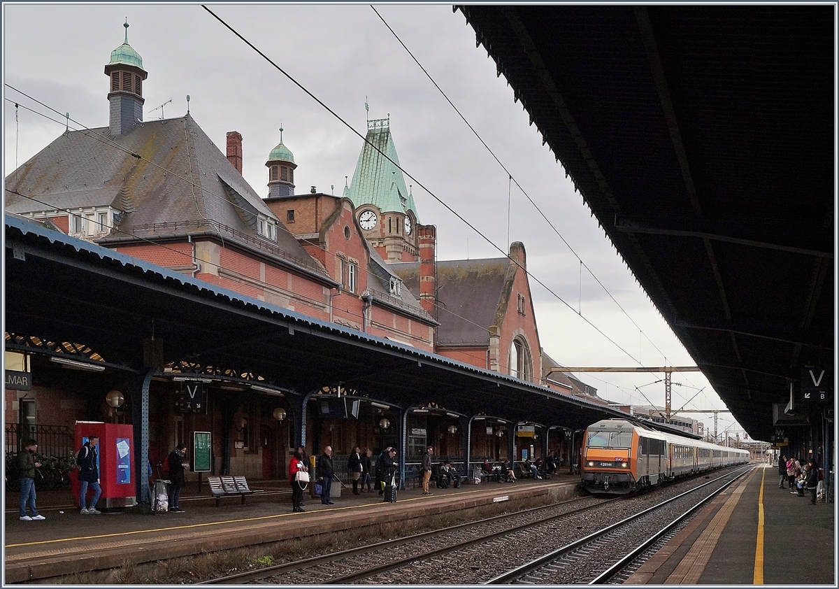 Immer wieder eindrücklich sind die 200 km/h schnellen TER 200, die zwischen Strasbourg und Basel verkehren. Das Bild zeigt die SNCF BB 26 141 (Sybic) welche mit ihrem TER 200 96214 in Colmar eintrifft.
Obwohl das schöne Empfangsgebäude in Colmar an ein Schottisches Schloss erinnert, wurde es nach angepassten Plänen des Bahnhofs von Danzig gebaut und 1907 eingeweiht. 13. März 2018