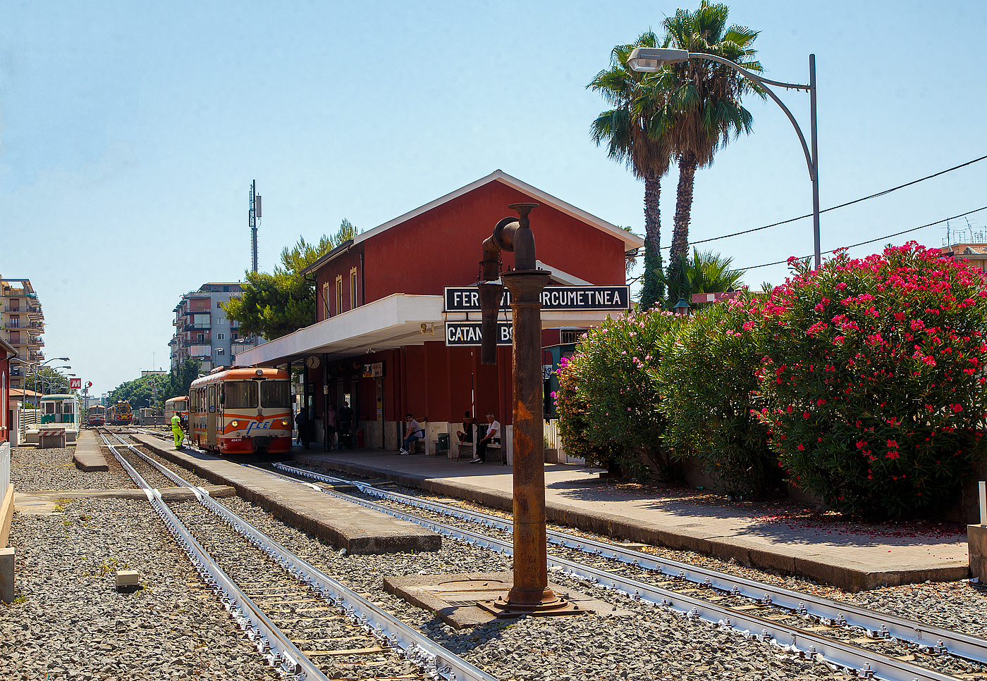Auch an und um Europas h�chsten aktiven Vulkan gibt es eine Bahn, die Schmalspurbahn die auch den Namen des Vulkans (�tna / italienisch Etna) in sich tr�gt, die Ferrovia Circumetnea (FCE).

Die Ferrovia Circumetnea (FCE), auch Circumetnea, ist eine regionale Nahverkehrsgesellschaft auf Sizilien, die eine 950 mm-Schmalspurbahn fast rund um den �tna betreibt. Nach der kompletten Stilllegung des ehemals ausgedehnten FS-Schmalspurbahnnetzes Siziliens ist sie die letzte verbliebene Schmalspurbahn auf der Insel. Mit einer Streckenl�nge von fast 111 km umrundet sie, zwischen Catania Borgo und Riposto, fast den kompletten 3.357 m hohen �tna. Leider l�sst der Fahrplan sehr zu w�nschen �brig, mal eben einmal rundherum fahren ist nicht so einfach. Zwischen Randazzo und Riposto finden nur wenige Zugfahrten am Tag statt. Zudem ruht sonntags der ganze Bahnbetrieb. 

Im Bahnhof Catania Borgo steht am 20.07.2022 der dieselelektrische Triebwagen FCE ADe 15 nach Patern� zur Abfahrt bereit.

10 dieser dieselelektrischen Triebwagen (ADe 11 bis 20) wurden Ende der 1970er-Jahre von OMS, TIBB und Fiat Ferroviaria f�r die Ferrovia Circumetnea (FCE) gebaut, heute sind noch 8 vorhanden. 

TECHNISCHE DATEN:
Hersteller: OMS, TIBB,  Fiat Ferroviaria 
Gebaute: 10
Spurweite: 950 mm
Achsfolge: Bo' Bo'
Treibraddurchmesser: 750 mm (neu)
H�chstgeschwindigkeit: 80 km/h
