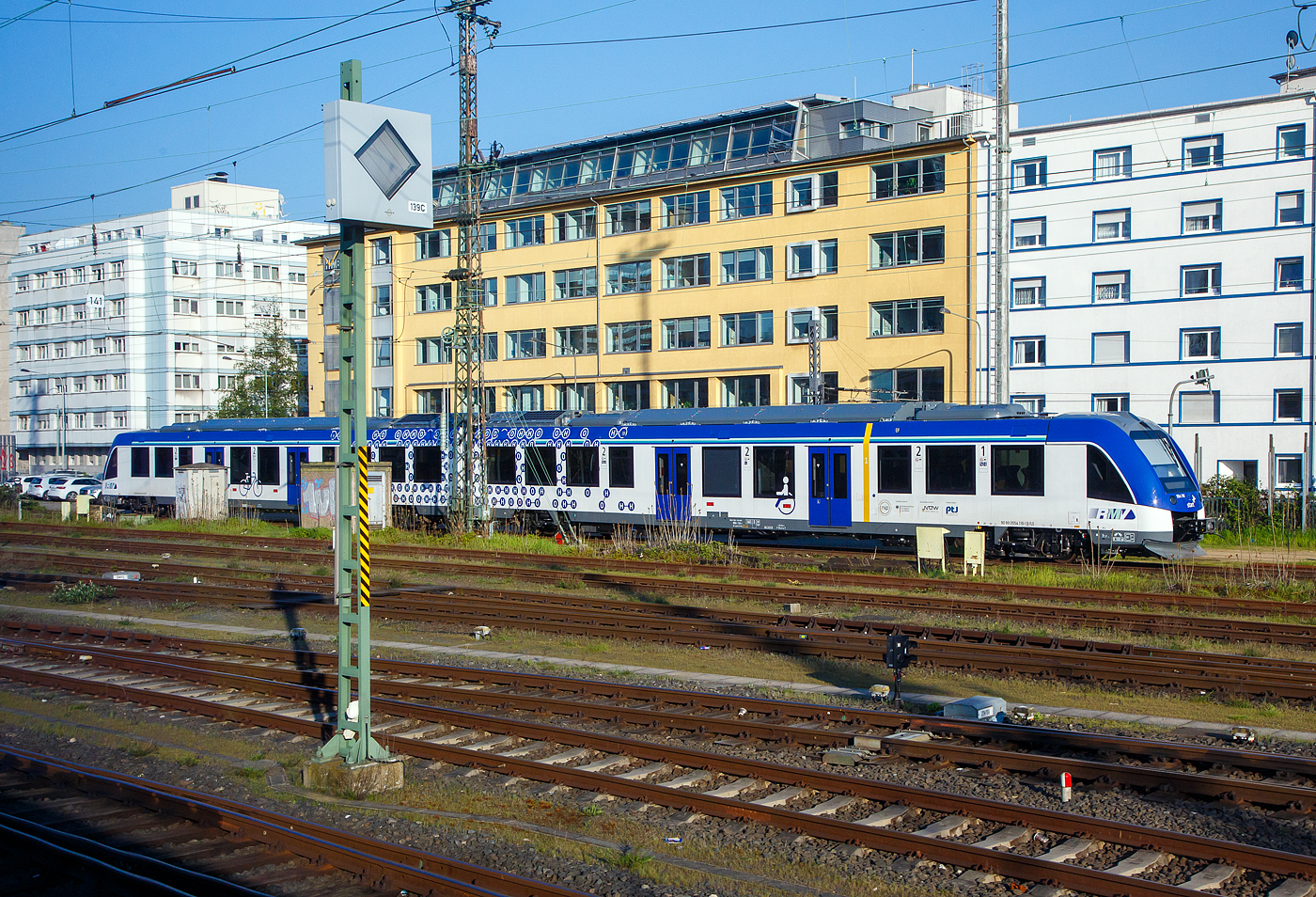 Das ist Klimaschutz....
Der zweiteilige (mit Wasserstoff fahrende) Brennstoffzellentriebzug 554 110 / 554 610 (90 80 0554 110-1 D-TLS / 90 80 0554 610-0 D-TLS), ein ALSTOM Coradia ILint 54, vom Fahrzeugmanagement Region Frankfurt RheinMain GmbH (fahma), betrieben durch die Regionalverkehre Start Deutschland GmbH, ist am 21.04.2023 beim Hauptbahnhof Frankfurt am Main abgestellt, aus einem fahrenden Zug heraus (durch die Scheibe) fotografiert.

Der ILint 54 wurde 2022 von ALSTOM Transport Deutschland GmbH (vormals LHB) in Salzgitter-Watenstedt unter der Fabriknummer D041461-010 gebaut.

Die Regionalverkehre Start Deutschland GmbH betreibt seit Dezember 2022 RMV-Taunusnetz. Das Besondere an diesem Netz (RB 11, RB 12, RB 15 und RB 16) ist, hier kommt ab der Inbetriebnahme sukzessive die gr��te Wasserstoffzugflotte der Welt auf die Schiene. Letztendlich werden im gesamten Netz 27 wasserstoffbetriebene Fahrzeuge vom Typ Coradia iLint des Herstellers Alstom zum Einsatz kommen.  Die fahma hat die Z�ge 2019 bestellt und stellt diese dem Betreiberunternehmen zu Verf�gung. Die neuen zweiteiligen Triebz�ge l�sen die dort fahrenden Z�ge des Typs Lint 41/H der fahma ab, die auf einer anderen Strecke weiter eingesetzt werden. Ausgemustert wird hingegen der Zugtyp VT/2E der HLB bzw. des Verkehrsverbands Hochtaunus.

Die fahma hat neben der Beschaffung der Z�ge auch die sichere Versorgung mit Wasserstoff, die Instandhaltung und das Vorhalten von Reservekapazit�ten f�r die kommenden 25 Jahre beauftragt. Die Versorgung mit Wasserstoff bietet Alstom in Kooperation mit der Infraserv GmbH & Co. H�chst KG an. Dabei befindet sich die Tankstelle auf dem Gel�nde des Industrieparks Frankfurt-H�chst.

Der Coradia iLint ist weltweit der erste Personenzug, der mit einer Wasserstoff-Brennstoffzelle betrieben wird, die elektrische Energie f�r den Antrieb erzeugt. In der Traktionsbatterie werden der vor�bergehend �bersch�ssig erzeugte Strom sowie die bei Bremsvorg�ngen zur�ckgewonnene Energie zwischengespeichert. Die umfangreich und komfortabel ausgestatteten Triebfahrzeuge sind so leise wie ein Elektro-Triebfahrzeug und emissionsfrei, weil sie lediglich Wasserdampf und W�rme an die Umwelt abgeben.

Die Wasserstofftriebz�ge:
Ein Triebwagen besteht aus zwei Wagenteilen, die jeweils auf zwei Drehgestellen (je ein Trieb- und ein Laufdrehgestell) ruhen. 

Die Energieerzeugung geschieht durch eine teilautonome Wasserstoff-Brennstoffzellenanlage zur Erzeugung elektrischer Energie. Die Antriebsleistung erfolgt durch 2 Drehstrom-Asynchronmotoren mit einer Leistung je 380 KW. In der Traktionsbatterieanlage  (Lithium-Ionen-Batterien) werden der vor�bergehend �bersch�ssig erzeugte Strom, sowie die bei Bremsvorg�ngen zur�ckgewonnene Energie zwischengespeichert. Die maximale (volle) Treibstofftankkapazit�t betr�gt 2 x 125 Kg Wasserstoff bei 350 bar und 15� C, h�rt sich wenig an, aber Wasserstoff hat eine sehr hohe Energiedichte. So erbeben die 125 kg H x 33 kWh/kg stolze 4.125 kWh. F�r die gleiche Energieleistung w�re z.B. Erdgas 8x schwerer. Zur Veranschaulichung ein beladener Lkw ben�tigt ca.  50-70 kg Wasserstoff, um 500 bis 600 km weit zu fahren.

Eine Mehrfachtraktion von bis zu 4 Fahrzeugen ist m�glich. F�r eine Fremdeinspeisung sind beidseitig au�en Anschl�sse  f�r 3x400V AC 32A vorhanden. An den Einstigen sind f�r die Spalt�berbr�ckung am Bahnsteig Schiebetritte vorhanden. F�r Rollstuhlfahrer werden zwei ausklappbar Rampen mitgef�hrt. Ein Triebwagen hat eine Klimaanlage getrennt f�r Fahrgastraum und F�hrerraum, ein Fahrerassistenzsystem, ein Fahrzeugdiagnosesystem, sowie ein automatisches Fahrgastz�hlsystem. Im Innenraum ist eine Toilette (Universal-WC) mit geschlossenem System eingebaut, zudem sind ein Fahrgast-WLAN, Laptop-Steckdosen an 50 % der Festsitze, ein Fahrgast-Informationssystem (�ber LCD-Flachbildschirme) und eine Video�berwachung des ganzen Innenraumes vorhanden.

Die Bef�rderungskapazit�t eines Treibwangens:
Ein Treibwagen hat insgesamt 160 Sitzpl�tze, davon 122 feste Sitze in der 2. Klasse und 16 in der 1. Klasse, zudem 22 Klappsitze. Rechnerisch (4 Pers./m�) sind maximal 144 Stehpl�tze m�glich. Zudem sind 2 Rollstuhl- und 12 Fahrradabstellpl�tze vorhanden, dadurch reduzieren jedoch (je nach Anzahl) die Klappsitze und Stehpl�tze. Bei voller Auslastung betr�gt das Betriebsgewicht ca. 107 t. 

TECHNISCHE DATEN:
Spurweite: 1.435 mm
Achsfolge: B’2’+2’B’
L�ngsdruckfestigkeit:1.500 kN
Fahrzeugl�nge �ber Kupplung:  54.270 mm
Fahrzeugbreite: 2.730 mm (3.030 mm mit ausgefahrenem Schiebetritt)
Maximale Fahrzeugh�he (�ber SO):  4.300 mm
Einstiegh�he (�ber SO): ca. 810 mm 
Fu�bodenh�he im Hochflurbereich: 1.190 mm
Anzahl der T�ren je Seite: 4 (1 x mit ausklappbarer Rollstuhlrampen)
Lichte Weite x H�he der T�ren: 1.300 x 2.015 mm
Installierte Leistung: 2 x380 kW
Leistungs�bertragung: elektrisch
Motoren: 2 Drehstrom-Asynchronmotoren
H�chstgeschwindigkeit: 140 km/h 
Maximale Streckenneigung:  40 ‰
Betriebsgewicht: ca. 107 t
Maximale Achslast: 18 t 
Treibstofftankkapazit�t: 2 x 125 Kg Wasserstoff bei 350 bar und 15� C
Bremsen: Wellenscheibenbremsen,ED- und EP-Bremsanlage, indirekte und Mg-Bremse, Feststellbremsen 
Kupplung: Mittelpufferkupplung Schaku Typ 10
kleinster befahrbarer Gleisbogen: R 150 m (Normal) / R 100 m (Werkstatt)

Der Coradia iLint ist weltweit der erste Personenzug, der mit einer Wasserstoff-Brennstoffzelle betrieben wird, die elektrische Energie f�r den Antrieb erzeugt. Dieser emissionsfreie Zug ist ger�uscharm und gibt lediglich Wasserdampf und Kondenswasser ab. Der iLint zeichnet sich durch die Kombination verschiedener innovativer Konzepte aus: saubere Energieumwandlung, flexible Energiespeicherung in Batterien sowie smartes Management von Antriebskraft und verf�gbarer Energie. Gezielt entwickelt f�r den Einsatz auf nichtelektrifizierten Strecken, erm�glicht er einen sauberen, nachhaltigen Zugbetrieb unter Beibehaltung einer hohen Leistung.  

Pers�nlicher Verbesserungsvorschlag:
Vielleicht k�nnte man unter Oberleitungen direkt elektrisch fahren. Ja daf�r braucht der Zug nicht nur einen Stromabnehmer, sondern auch einen Trafo usw., aber Reichweite w�rde erh�ht. 

