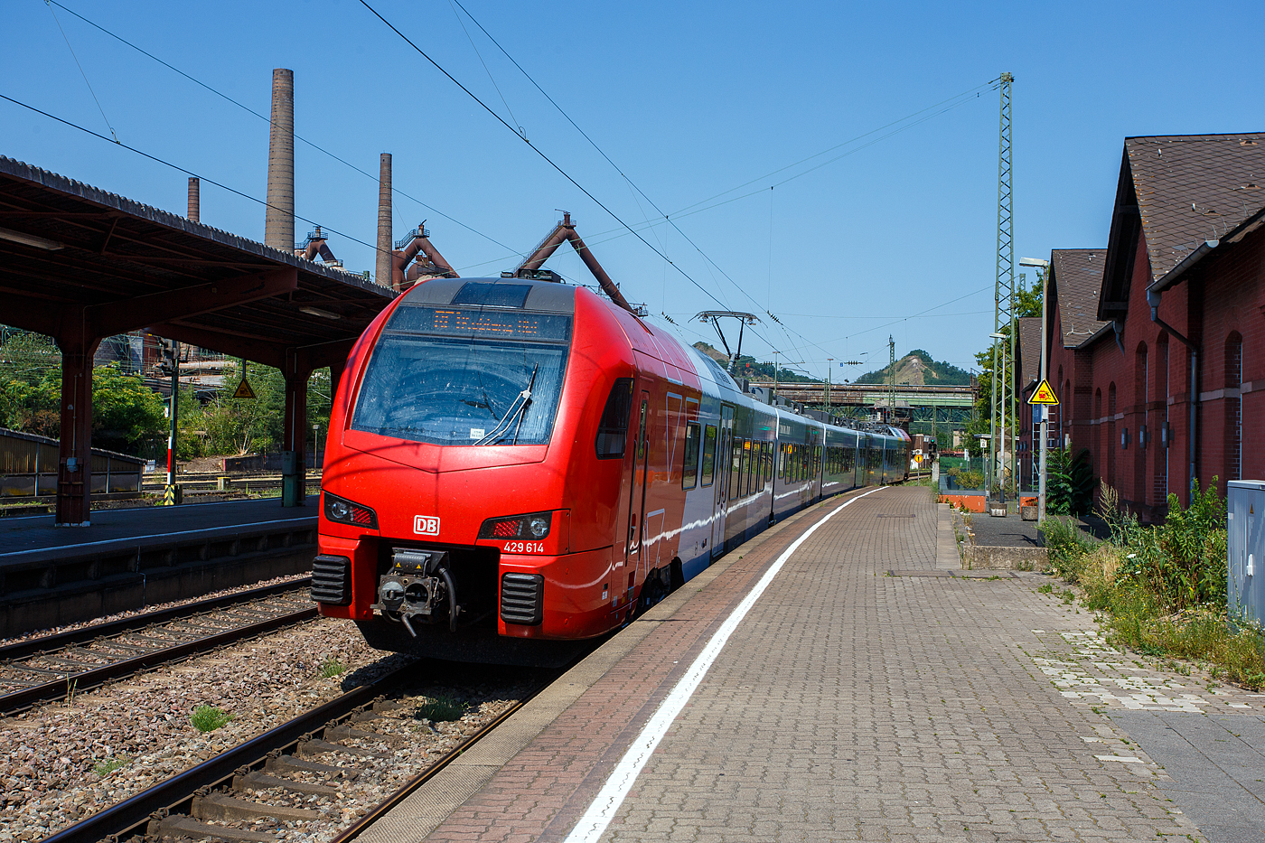 Der fünfteilige SÜWEX Stadler FLIRT 3 – 429 114 / 429 614, als RE 1  Südwest-Express  (Kaiserslautern – Trier – Koblenz), verlässt am 01 Juli 2025 den Bahnhof Völklingen und fährt weiter in Richtung Dillingen. Ich finde das neue Farbdesign der SÜWEX (Südwest-Express), mit den nun roten Triebwagenköpfen, ist für mich gelungener als das alte Farbdesign.

Im Hintergrund das Ziel unserer Reise an diesem Tag, das Weltkulturerbe Völklinger Hütte. Die Völklinger Hütte ist weltweit das einzige Eisenwerk aus der Blütezeit der Industrialisierung, das vollständig erhalten ist. Seit 1994 zählt es zum UNESCO-Weltkulturerbe.