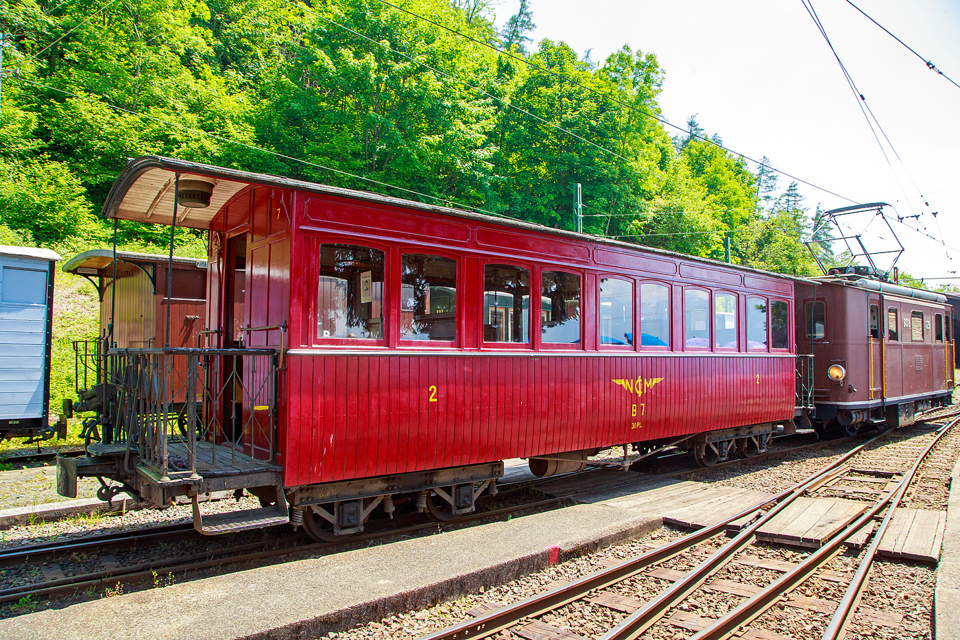 Der vierachsige 3.Klasse Großraum-Plattformwagen C4 7 der Museumsbahn Blonay-Chamby (beschriftet jedoch als B 7), ex NStCM C 7, am 27.05.2023 im Museumsareal in Chaulin. der Museumsbahn Blonay-Chamby. 

Der Wagen wurde 1910 für die französische Chemins de Fer de Haute Saône vom Hersteller Ateliers de construction du Nord de la France (ANF Blanc-Misseron) als Salonwagen A7 gebaut. 1934wurde er von der Le Morez - La Cure (MLC) gemietet und 1938 endgültig gekauft. Im Jahr 1946 übernahm ihn die Chemin de fer Nyon–St-Cergue–Morez (NStCM), die Polstersitze wurden durch Holzbänke ersetzt und der Wagen wurde zum C 7. Die Museumsbahn Blonay-Chamby konnte den Wagen 1993 erwerben.

TECHNISCHE DATEN:
Baujahr: 1910
Hersteller: ANF Blanc-Misseron
Spurweite: 1.000 mm (Meterspur)
Achsanzahl: 4
Länge über Puffer: 10.940 mm
Länge Wagenkasten: 10.000 mm (mit Plattformen)
Drehzapfenabstand: 5.600 mm
Achsabstand im Drehgestell: 1.240 mm
Eigengewicht: 8,5 t
Sitzplätze: 30