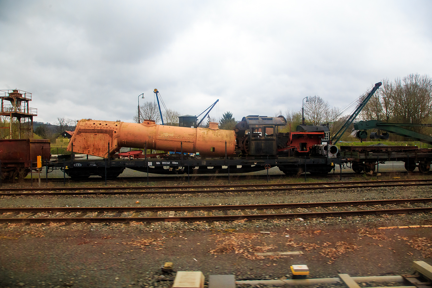 Der vierachsige Drehgestell-Schienenwagen (Drehgestell-Flachwagen) DR Köln 918 041 SSlma (DB SSlma 44), beladen mit Kessel und Teilen einer Dampflok, am 17 April 2023 im DDM - Deutsches Dampflokomotiv-Museum in Neuenmarkt (aufgenommen aus einem Zug heraus).

Mit dem Aufkommen der Schweißtechnik und der Aufrüstung des Deutschen Reiches entstand Bedarf an einem neuen vierachsigen Schienenwagen. 1934 lieferte SEAG (Siegener Eisenbahn Bedarf AG in Dreis-Tiefenbach) die ersten beiden Versuchswagen. Sie bestanden aus St 52 und hatten jeweils ein abnehmbares Bremserhaus aus Holz oder Stahl. Die weiteren Lieferungen bis 1939 bestanden ebenfalls aus St 52, hatten drei Querträger und sieben Rungenpaare. Das Bremserhaus war abnehmbar. Ab 1941 baute man eine veränderte Variante. Diese bestand jetzt aus dem schwächeren St 37, was dazu führte, dass man einen vierten Querträger vorsehen musste. Seitlich gab es jetzt nun acht Rungenpaare (wie bei diesem). Für Fahrzeugtransporte hatte der Bremserstand nur noch ein umlegbares Bühnengeländer. Neben den Lieferungen an die DR erhielt auch die Wehrmacht diese Wagen und setzte sie für militärische Zwecke, u.a. in den Zügen der mobilen V2-Rampen, ein. Insgesamt wurden bis Kriegsende ca. 3.500 Wagen gebaut. Nach 1945 waren die geschweißten Schienenwagen über halb Europa verteilt. Die DB hatte nach Kriegsende ca. 1.400 Wagen im Bestand, die DR schätzungsweise 500. Bei beiden Bahnverwaltungen wurden die Wagen lange eingesetzt und schieden erst in den 1980er-Jahren aus. Noch 1979 hatte die DB über 1.000 der als R 672 bezeichneten Wagen im Einsatz. 
