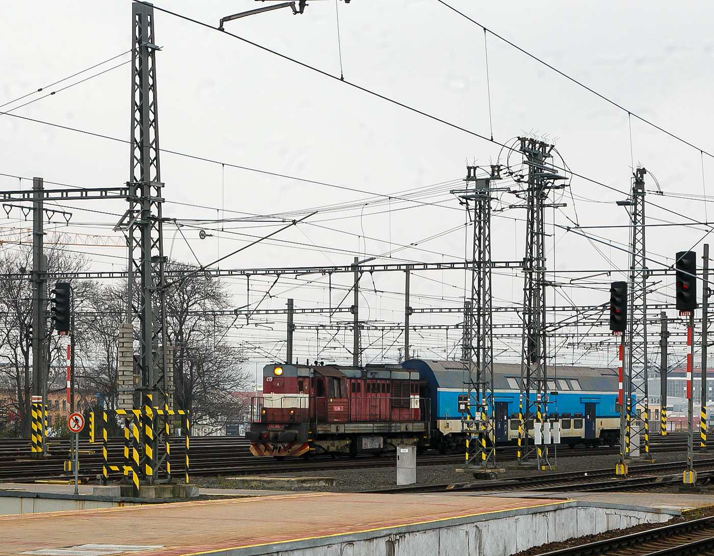 Die ČD 742 086-2 (CZ- ČD 92 54 2 742 086-2) f�hrt am 23.11.2022, mit dem  2. Klasse klimatisierten Doppelstock-Reisezugwagen, CD-CZ 50 54 26-18 141-6, der Gattung Bdmteeo 296 (ex CD-CZ 50 54 26-18 141-6, Bmto 292), in den Prager Hauptbahnhof (Praha hlavn� n�dra��) ein. Der 44 t schwere Wagen verf�gt �ber 126 Sitzpl�tze, 8 Stellpl�tze f�r Fahrr�der und ein geschlossenes WC-System.

Die Diesellok  Kocour   oder  Tranzisto   (Kater, Transistor):
Die ČSD-Baureihe T 466.2, ab 1988 Baureihe 742 sind dieselelektrische G�terzug- und Rangierlokomotiven der ehemaligen Tschechoslowakischen Staatsbahn (ČSD). Die Entwicklung begann 1970 mit den beiden Prototypen der BR T 475.15 (744.5). 

Das Leistungswachstum in der Motortraktion sowie die Notwendigkeit von Fortschritten bei der Erneuerung der Dampftraktion und der k�nftigen Typenvereinheitlichung des Motorlokparks veranlassten das Verkehrsministerium, die Beauftragung der Entwicklung und anschlie�enden Produktion einer neuen Lokomotive zu pr�fen. Diese sollte f�r mittelschweren bis schweren Rangierdienst, leichteren Gleisdienst, aber auch im G�ter- und Personenverkehr, bestimmt sein.

Zwei Prototyp-Lokomotiven der Reihe T 475.15 (744.5) wurden 1970 von ČKD in Praha gebaut, wurden aber von der ČSD als ungen�gend abgelehnt. Dies lag haupts�chlich an ihrem F�hrerstand,  w�hrend die ČSD einen Turmf�hrerstand mit guter Sicht verlangte, hatten diese Lokomotiven einen F�hrerstand neben dem hinteren Ende der Lokomotive, sodass die Aussicht nicht sehr zufriedenstellend war. Die Maschinen der Baureihe T 475.15 wurden daher verworfen und stattdessen die neuen Lokomotiven der Baureihe T 466.0 (735) produziert. Die Produktion erfolgte ab 1972 im Turčiansk� stroj�rny in Martin. 1973 begann bei ČKD Prag die Produktion neuer Lokomotiven der Reihe T 448.05 (740.5), die f�r den Bedarf gro�er Industrieunternehmen und f�r den Export bestimmt waren. Die Produktion von Lokomotiven T 466.0 (735) bei TS Martin verz�gerte sich noch, die Entwicklung von Lokomotiven der Baureihe T 466.1 blieb erfolglos, au�erdem war geplant, die Produktion von Lokomotiven bei TS Martin einzustellen und das Werk auf die Waffenproduktion zu konzentrieren . Auch die bereits produzierten T 466.0 (735) Maschinen waren im Betrieb sehr unzuverl�ssig. Die Situation in der Flotte der ČSD-Motorlokomotiven ist daher unertr�glich geworden. Deshalb hat sich die ČSD eine Notl�sung einfallen lassen: 1976 bestellten sie bei der ČKD 60 neue Lokomotiven der Baureihe T 466.2 (742), die genau aus den Industriemaschinen der T 448.05 (740.5) entstehen sollten. Die Serie, die bereits seit drei Jahren in der Industrie im Einsatz war, mit zudem sehr guten Ergebnissen. Die Liste der erforderlichen Umbauten war recht lang: Gewichtsreduzierung, Umbau des Triebwerks, Einbau einer Zugsicherung, Umbauten im elektrischen Teil, Umbau der Bremsen.1977-78 wurden 60 Lokomotiven der 1. Serie gebaut geliefert und die neuen Maschinen wurden fast sofort auf CSD in Betrieb genommen. Die 2. Serie folgte sofort und eine weitere danach. Die Produktion der Lokomotiven T 466.2 (742) f�r die ČSD endete mit der 9. Serien im Jahr 1986; insgesamt erwarb ČSD 453 dieser Lokomotiven. W�hrend der langj�hrigen Produktion gab es mehrere partielle 

Modifikationen an der Konstruktion der Maschine – ab der 2. Serie mehrgliedrige Lenkung und Zugkraftw�hler, ab der 3. Serie eine Knickbr�cke seitlich am k�rzeren Vorbau, ab der 6. Serie wurden Jalousien auf dem Dach der Lokomotive installiert und ab der 7. Serie neue Fahrmotoren. 41 Lokomotiven wurden f�r den Bedarf der Industrie geliefert, Maschinen auf Basis der Baureihe T 466.0 ČSD wurden auch nach Vietnam und Bangladesch geliefert. Nach der Produktion von Lokomotiven T 466.2 (742) f�r ČSD erfolgte 1987-88 die Produktion von abgeleiteten Lokomotiven T 466.3 (743) f�r Adh�sionsbetrieb auf Steilstrecken.

TECHNISCHE DATEN der BR 742, ex T 466.2:
Hersteller: ČKD Praha
Baujahre: 1977 bis 1986
Hergestellt e Anzahl: 453 f�r die ČSD (in 9 Serien), 41 weiter f�r andere
Spurweite: 1.435 mm (Normalspur)
Achsfolge: Bo'Bo'
L�nge �ber Puffer: 13.580 mm ( am 4. Serie13.600 mm)
H�he: 4.472 mm
Breite: 3 130 mm
Drehzapfenabstand: 6.700 mm
Achsabstand im Drehgestell: 2.400 mm
Treibrad-�: 1.000 mm (neu) / 920 mm (abgenutzt) 
Dieselmotor: 6-Zylinder-Viertakt-Reihen- Dieselmotor mit Direkt-Einspritzung und Turbolader vom Typ ČKD  K 6 S 230 DR
Motorhubraum: 64,75 Liter (Zylinder-� 230 mm / Kolbenhub 260 mm)
Kompressionsverh�ltnis: 12,5 : 1
Nenndrehzahl: 1.250 U/min (Leerlaufdrehzahl 510 U/min)
Motorgewicht (ohne Generator): 7.700 kg
Achs�bersetzung: 1:4,8125
Dauermotorleistung: 883 kW (1.200 PS)
Leistung des Traktionsgenerators: 780 kVA
Leistungs�bertragung: dieselelektrisch
Fahrmotorentyp: TE 005 E / ab 7. Serie TE 015 C
Antriebsmotorleistung: 195 kVA
H�chstgeschwindigkeit: 90 km/h
Dienstgewicht: 64 t
Anfahrzugkraft: 192kN
Dauerzugkraft: 121 kN
Max. Tankinhalt: 4.000 l
Kleinster bef. Halbmesser: R 80 m

Quellen: Wikipedia, atlaslokomotiv.net
