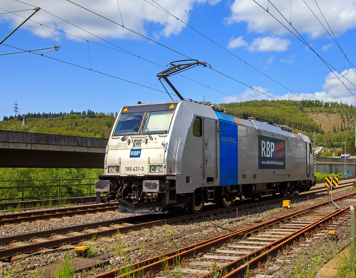 Die an die RBP - Rheinische Bahnpersonal- und Verkehrsgesellschaft mbH (Siegburg) vermietete Railpool 186 431-3  (91 80 6186 431-3 D-Rpool) f�hrt am 16.05.2023 als Lz (Lokzug) bzw. auf Tfzf (Triebfahrzeugfahrt) durch Niederschelden in Richtung Siegen. Hinweis ich stehe an der Schranke vom B� 343 – km 112,183 der Siegstrecke.

Die Bombardier TRAXX F140 MS(2E) wurde 2015 von Bombardier in Kassel unter der Fabriknummer 35185 gebaut und an die Railpool GmbH (M�nchen) ausgeliefert. Die Multisystemlokomotive hat die Zulassungen bzw. besitzt die L�nderpakete f�r Deutschland, �sterreich, und Tschechien (D/A/CZ). Urspr�nglich war sie f�r Polen, Slowakei, Ungarn und die Niederland (PL/SK/HU/NL) zugelassen, aber aktuell sind diese L�nderk�rzel an die Lok durchgestrichen.


Der derzeitige Mieter die RBP - Rheinische Bahnpersonal- und Verkehrsgesellschaft mbH in Siegburg, ist eine junge und moderne Eisenbahnverkehrsgesellschaft, speziell f�r Bahn- und Verkehrsbetriebe. 