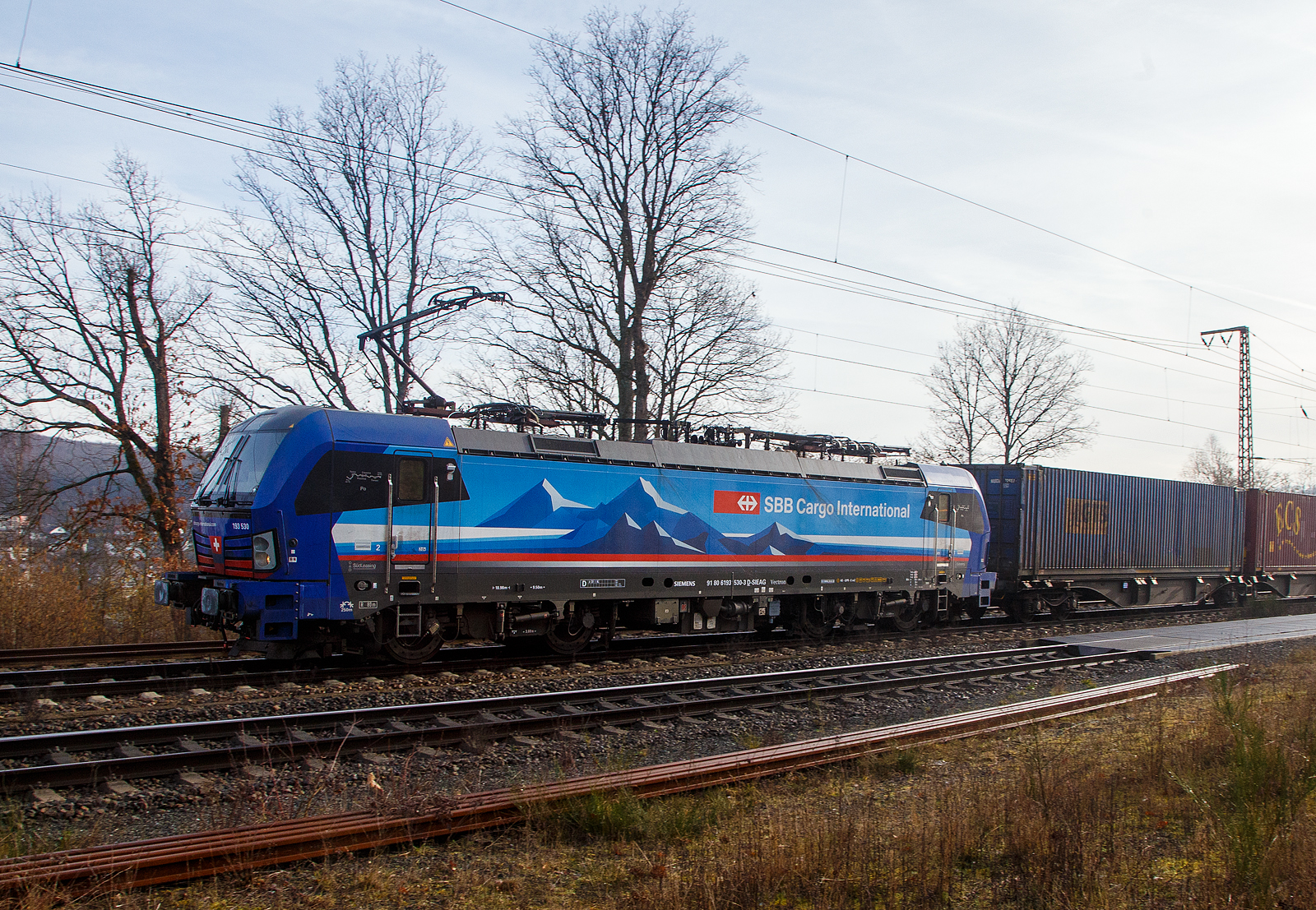 Die an die SBB Cargo International AG vermietete 193 530-3  Po  (91 80 6193 530-3 D-SIEAG) der SüdLeasing GmbH (Stuttgart, eingestellt in Deutschland durch Siemens) fährt am 22.02.2023, mit einem Containerzug, durch Wilnsdorf-Rudersdorf (Kr. Siegen) in Richtung Siegen. 

Der SIEMENS Vectron MS wurde 2019 von Siemens Mobilitiy in München-Allach unter der Fabriknummer 22726 gebaut. Eigentümer ist die Südleasing GmbH in Stuttgart (LBBW-Tochter) die 20 dieser Loks an die SBB Cargo International vermietet hat, eingestellt sind sie in Deutschland durch die Siemens Mobilitiy. 

Diese Mehrsystem-Loks sind für den Einsatz auf dem Rhein-Alpen-Korridor vorgesehen und sind für den Betrieb in Deutschland, Österreich, Schweiz, Italien und den Niederlanden (D/A/CH/I/NL) ausgelegt. Sie verfügen über eine Leistung von 6,4 MW (160 km/h) und sind neben den nationalen Zugsicherungssystemen mit dem Europäischen Zugsicherungssystem (ETCS) ausgestattet.
