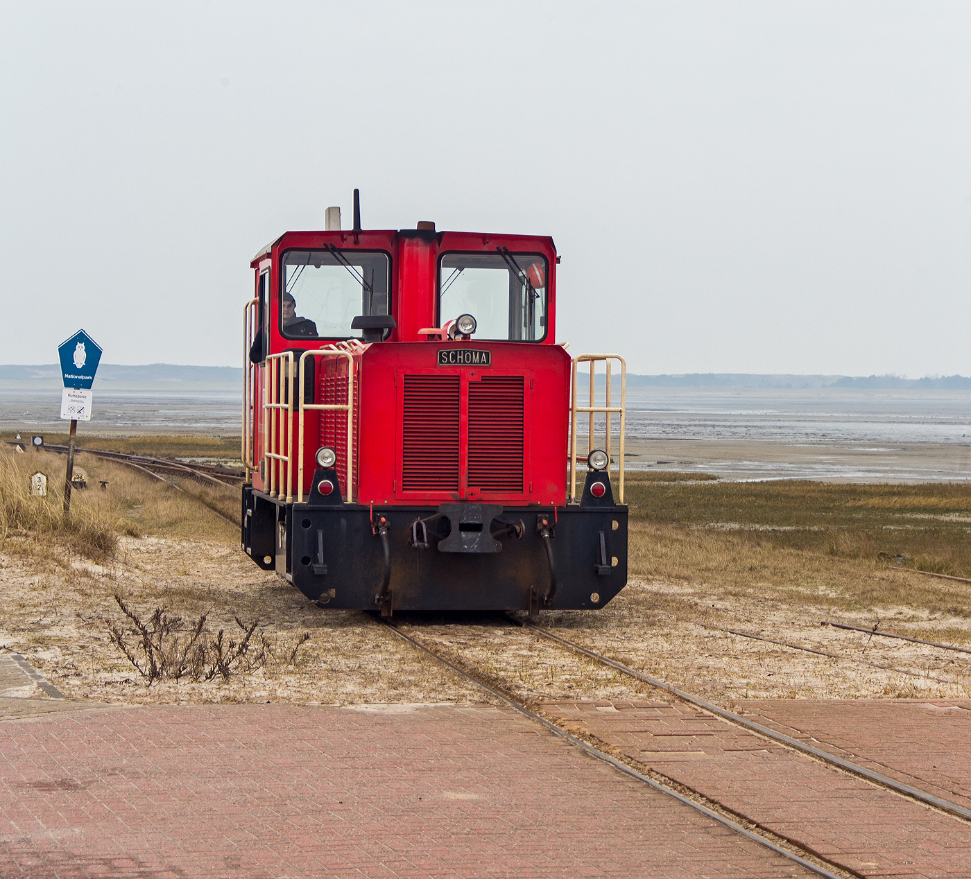 Die DB 399 108-0 (98 80 3399 108-0 D-DB) der Wangerooger Inselbahn rangiert am 12 März 2024 am Westanleger Wangerooge, an den nun leeren Personenzug (5 Wagen sowie zwei Flachwagen für Gepäckcontainern) heran.

Die meterspurige Lok wurde 1999 von SCHÖMA - Christoph Schöttler Maschinenfabrik GmbH in Diepholz unter der Fabriknummer 5600 für die Inselbahn Wangerooge der Deutsche Bahn AG gebaut und geliefert.
