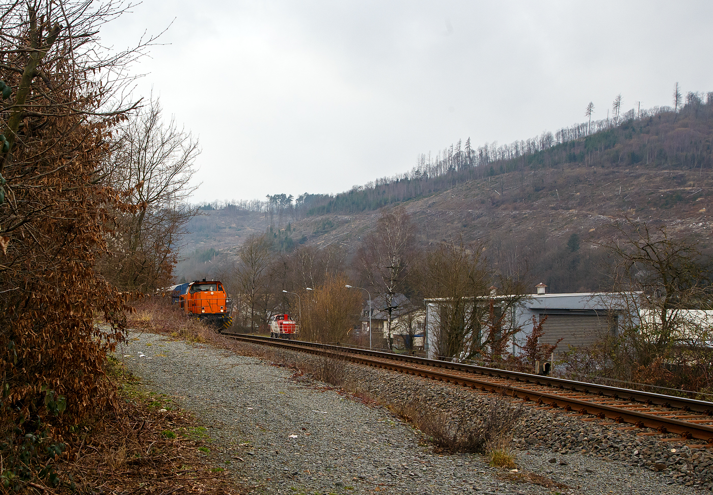 Die KSW 42 (92 80 1277 902-3 D-KSW), eine Vossloh MaK G 1700 BB der KSW (Kreisbahn Siegen-Wittgenstein), f�hrt am 10.02.2023, mit einem �bergabe-G�terzug, von Herdorf �ber Hellertalbahn, via Haiger nach Dillenburg, w�hrend rechts unten am KSW Rangierbahnhof Herdorf (Freien Grunder Eisenbahn KSW NE447 / DB-Nr. 9275) die Die KSW 47 (92 80 1271 027-5 D-KSW), ex D 2 der HFM, eine Vossloh G 1000 BB steht.

Im Bild ganz rechts der Lokschuppen der KSW, ex Freien Grunder Eisenbahn.
