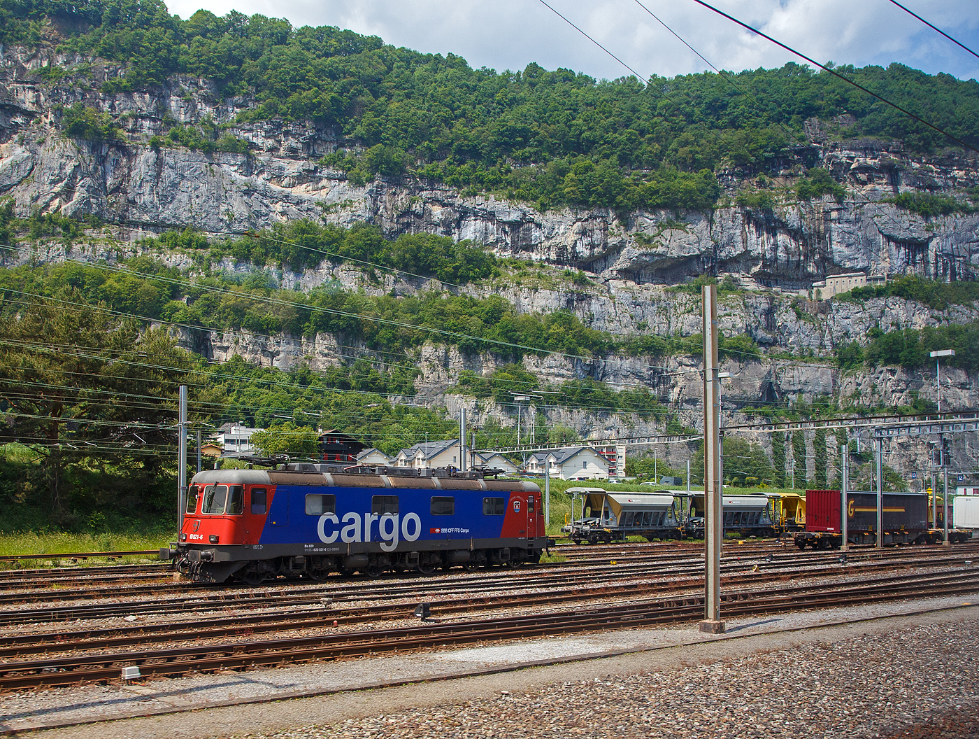 Die Re 620 021-6 “Taverne-Torricella“ (91 85 4620 021-6 CH-SBBC) der SBB Cargo AG, ex SBB Re 6/6 – 11621, ist am 28.05.2023 beim Bahnhof St-Maurice abgestellt, aufgenommen aus dem Zug heraus.

Die Re 6/6 wurde 1976 von der SLM in Winterthur (Schweizerische Lokomotiv- und Maschinenfabrik) unter der Fabriknummer 5008 gebaut, der elektrische Teil ist von BBC. Führerstands-Klimaanlagen wurden nachträglich eingebaut.