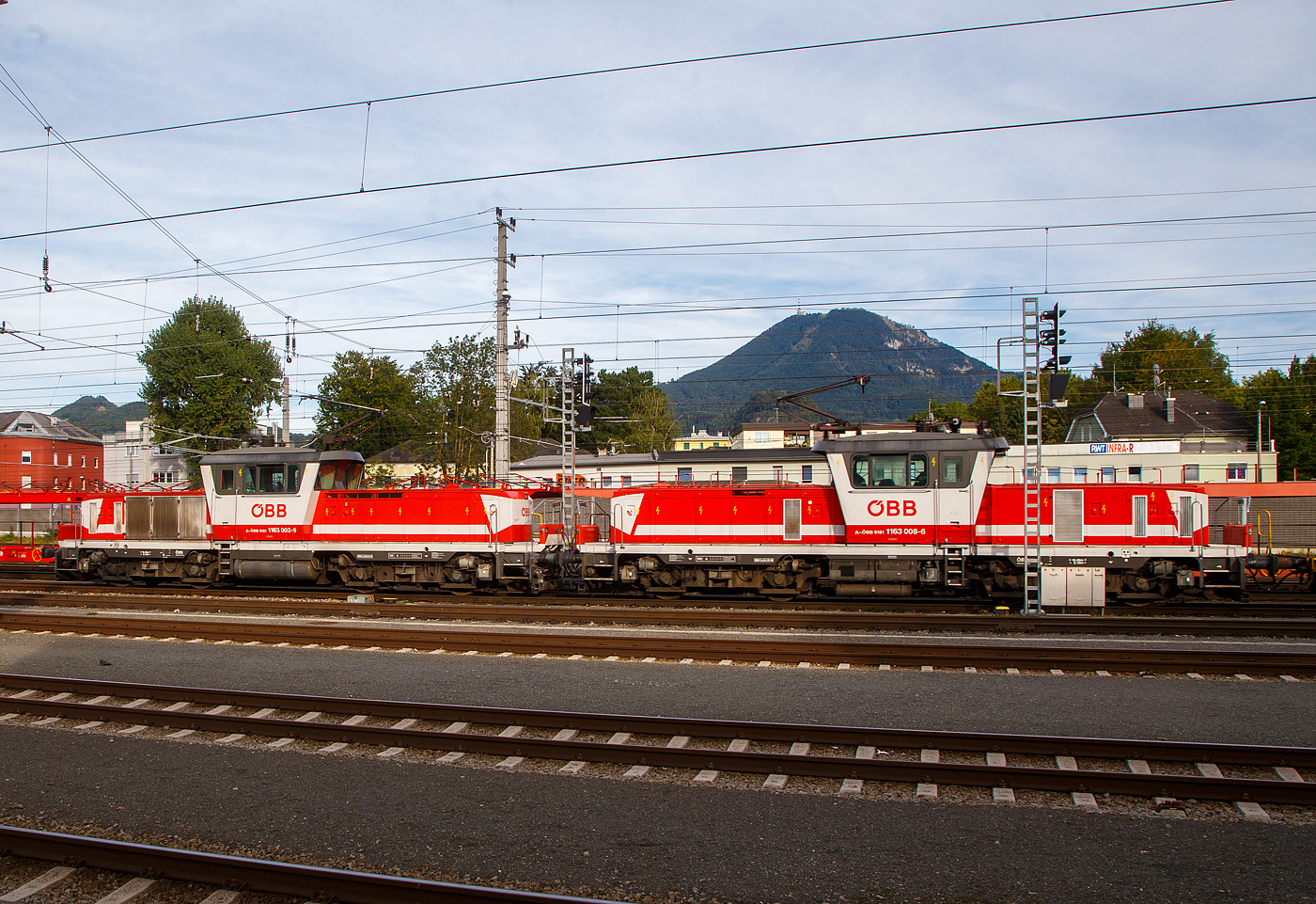 Dieter und Robert mit einem Containerzug....
Die beiden gekuppelten �BB 1163, die �BB 1163 002-9 „Dieter“ (A-�BB 91 81 1163 002-9) und die �BB 1163 008-6 „Robert“ (A-�BB 91 81 1163 008-6) fahren am 12.09.2022 vom Container Terminal Salzburg kommend, mit einem Containerzug durch dem Hauptbahnhof Salzburg.

Beide Loks wurden 1994 von der SGP Simmering-Graz-Pauker AG (ab 1996 Siemens SGP Verkehrstechnik GmbH) unter den Fabriknummern 80835 und 80841 gebaut, die elektrische Ausr�stung ist von ABB-Brown-Boveri-Werke AG und der ELIN Antriebstechnik GmbH. 

Die Reihe 1163 ist eine vierachsige, elektrische Verschublokomotive (Rangierlokomotive) der �sterreichischen Bundesbahnen (�BB). Sie stellt eine Weiterentwicklung der �BB Reihe 1063 dar und gilt als „Fl�sterlok“. Die Lieferung der Reihe 1063 endete im Herbst 1991, w�hrend deren fast neunj�hrigem Lieferzeitraum gewann die Halbleitertechnik noch mehr Dominanz im Triebfahrzeugbau, so flossen die gemachten Fortschritte in die Nachfolgebaureihe ein.

Mechanischer Teil:
Die Grundkonzeption stammt von der Vorg�ngerreihe 1063. Der Lokrahmen zieht sich �ber die ganze L�nge. Auf ihm sitzen die beiden im Gegensatz zur Vorg�ngerreihe wesentlich niedrigeren und schm�leren Vorbauten. Dazwischen ist der nach au�en „gew�lbte“ F�hrerstand angeordnet, der wie bei den beiden Reihen 1063 und 2068 �ber vier Bedienpulte verf�gt, aber eine verbesserte Rundum-Sicht aufweist. Vor den Vorbauten sind beidseitig Verschieberplattformen angebracht. Zwei zweiachsige Drehgestelle tragen den Lokrahmen. Der Transformator befindet sich unter dem F�hrerstand, die Fahrmotoren liegen in den Drehgestellen. Die Zug- und Bremskraft�bertragung erfolgt am tiefliegenden Drehzapfen. 

Elektrischer Teil:
Das Dach tr�gt einen Einholmstromabnehmer (Bauart VIII) samt Hauptschalter und Dachleitungen. Ein liegender Transformator mit �lk�hlung speist den Strom zum Netzstromrichter, der aus zwei ausgangsseitig parallel geschalteten Vierquadrantenstellern in GTO-Technik besteht. Der Gleichspannungszwischenkreis betr�gt 2500 V, die Resonanzfrequenz des Saugkreises 33,3 Hz. Der Antriebswechselrichter besteht aus drei gleichen GTO-Phasenmodulen, die parallel zum Zwischenkreis geschaltet sind und je eine Phase f�r die Fahrmotoren liefern. Die vier Motoren und das Antriebskonzept entsprechen der Reihe 1063, ebenso das Bremssystem, das au�erdem �ber eine Rekuperationsbremse verf�gt. Die Loks verf�gen auch �ber Sifa und Indusi. 

TECHNISCHE DATEN:
Gebaute Anzahl: 20 (1163 001 bis 1163 020)
Spurweite:  1.435 mm (Normalspur)
Achsformel:  Bo’Bo’
Begrenzungslinie : UIC 505-1
L�nge �ber Puffer:  16.400 mm
Drehzapfenabstand:  8.100 mm
Achsabstand in Drehgestell:  2.800 mm
Raddurchmesser:  1.145 mm (neu) / 1.065 mm (abgenutzt) 
Dienstgewicht: 80 t
Radfahrmasse: 20 t
Meterlast: 4.878 kg
H�chstgeschwindigkeit: 100 km/h 
Dauernennleistung:  1.600 kW
Maximalleistung: 2.000 kW 
Anfahrzugkraft:  260 kN
Stromsysteme: 15kV/16,7Hz
Antriebsart: GTO-Stromrichter und 4 Drehstrom Fahrmotoren und Tatzlagerantrieb
Motorentyp:  6FRA 5272
Zugelassen f�r Streckenklasse: D2 oder h�her
Kleinster befahrbarer Gleisbogen (Vmax= 10 km/h): R = 100 m
Bremsbauart: KE-GPR-E m Z
Dynamisches Bremssystem: Elektrodynamische R�ckspeisebremse
Max. Bremskraft der dynamischen Bremse: 120 kN

Quellen: �BB, �BB-Produktion GmbH und Wikipedia