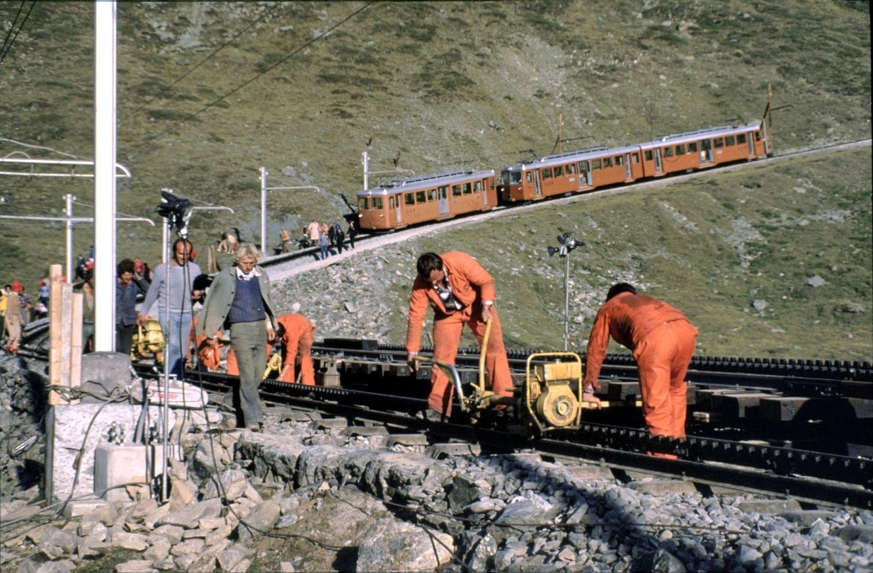Gornergratbahn, Reparaturarbeiten, Reisende müssen über die Baustelle umsteigen, am 22.08.1979. Der Bhe 2/4 und der Bhe 4/8 oben im Bild haben die Reisenden gebracht und warten auf die Züge aus dem Tal.