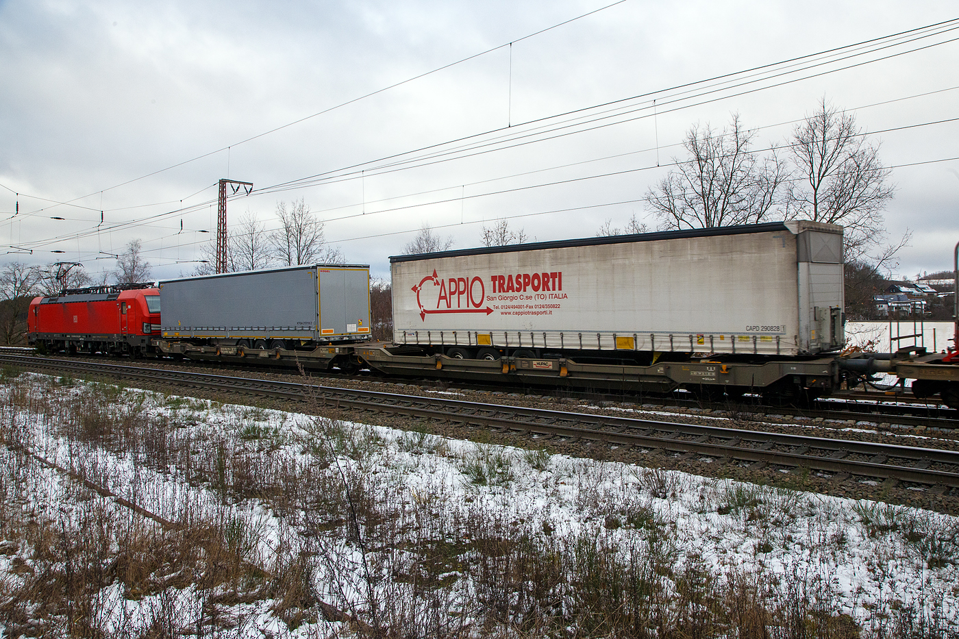 Hinter der DB 193 323-3....Der sechsachsige Gelenk-Taschenwagen (Doppeltaschenwagen in Gelenkbauart), 33 85 4956 771-7 CH-HUPAC der Gattung Sdggmrss, der HUPAC Intermodal SA, am 27.01.2023 im Zugverband bei der Durchfahrt in Rudersdorf (Kr. Siegen), im Zugverband bei der Durchfahrt in Rudersdorf (Kr. Siegen), hier beladen mit zwei Sattelanh�ngern.

Diese Wagen vom Typ T5/T3000e wurde von Tatravag�nka a.s. in Poprad (Slowakei) ab 2015 gebaut, die Entwicklung und auch Lizenzgeber ist die Ferriere Cattaneo SA in Giubiasco (Schweiz). Baugleiche Wagen sind auch bei anderen Halteren im Einsatz, die jeweils die Gattungskennzahl 4956 haben. M�gliche Ladeeinheiten sind zwei kranmanipulierbare Sattelauflieger oder alternativ bis zu vier Wechselbr�cken und/oder Container. Daf�r besitzt der Wagen einen dreifach verstellbaren St�tzbock sowie f�r die Ladungseinheiten feste und klappbare Aufsetzzapfen auf den Langtr�gern. Das maximale Zuladegewicht betr�gt f�r Sattelauflieger 2 � 40 t; die Basish�he liegt bei 270 mm �ber SO.

TECHNISCHE DATEN:
Spurweite: 1.435 mm
L�nge �ber Puffer: 34.200 mm
Drehzapfenabstand: 2 x 14.200 mm
Achsabstand in den Drehgestellen: 1.800 mm
Laufraddurchmesser: 920 mm (neu) / 860 mm (abgenutzt)
Ladel�nge: 2 � 16.185 mm
Eigengewicht: 36.200 kg
Max. Zuladung bei Lastgrenze S: 98,8 t (ab Streckenklasse D)
Max. Zuladung bei Lastgrenze SS: 83,8 t (ab Streckenklasse C)
Max. Geschwindigkeit: 100 km/h / bei Lastgrenze SS und leer 120 km/h
Kleinster  befahrbarer Kurvenradius: R 75 m (R 150 m im Zugverband)
Intern. Verwendungsf�higkeit: TEN – GE

Die Bedeutung der Gattungs- und Kennbuchstaben (hier  Sdggmrss):
S - Drehgestell-Flachwagen in Sonderbauart
d - f�r den Transport von Stra�enfahrzeugen eingerichtet
gg - f�r den Transport von Containern �ber 60 Fu� eingerichtet
m - bei mit sechs o. mehr  Rads�tzen Ladel�nge 18 m bis unter 22 m
r - Gelenkwagen
ss - H�chstgeschwindigkeit (beladen) bis zu 120 km/h