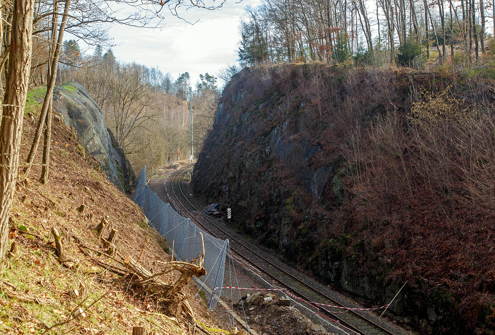 HLB Zug am 23.12.2022 auf der Hellertalbahn entgleist und die Strecke bleibt weiter lange, vermutlich bis Juni 2023, gesperrt...
Die Strecke der Hellertalbahn (KBS 462), beim Hp Königsstollen in Richtung Herdorf  (Hp Königsstollen) gesehen am 06.02.2023. Hier sieht man Tatsache das links beim alten Gleis bereits umfangreiche Hangsicherungsmaßnahmen stattgefunden haben. Rechts am aktiven Gleis sieht man das abgerutschte Material, welches am 23.12.2022 einen Triebwagen der RB 96 „Hellertalbahn“, den HLB VT 507, zur Entgleisung brachte. Verletzt wurde zum Glück niemand.

Derzeit muss man von einer Sperrung der Hellertalbahn bis zum Juni ausgehen. Ja, die Sicherheit geht vor!!! Aber ist wirklich keine kurzfristige Maßnahme möglich. Könnte man nicht einfach das aktive Gleis ins alte zweite Gleis verschwenken? 

Neben der Sperrung der Bahn, gibt es in Herdorf wegen Straßenbauarbeiten schon genug Probleme mit dem Umleitungsverkehr auf den Straßen. Hinzu kommt ab Anfang April ein weiteres Problem in der Verbindung zwischen Betzdorf und Herdorf, denn dann wird der vom Landesbetrieb Mobilität beauftragte Abriss und Neubau der Hellerbrücke in Herdorf beginnen. Die L284 soll dafür bis August gesperrt bleiben und in den ersten sechs Wochen auch die wichtige Umleitungsverbindung über die L285 nach Daaden.
