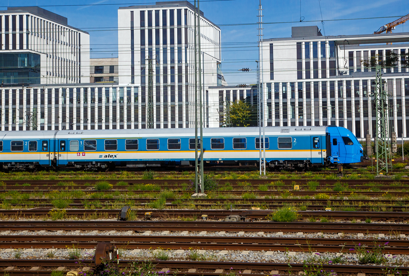 Ist das der neue alex-FLIRT 3.....Nein, ein FLIRT 3 steht nur hinter dem abgestellten alex-Zug.  Der 1./2. Reisezugwagen D-DLB 56 80 39-95 515-4, der Gattung ABvmz, der Die Länderbahn GmbH (alex) abgestellt am 13.09.2022 beim Hbf München. Der Wagen ist der ex DR 51 80 20-95 515 (Amz), ex 51 80 20-95 515-0 D-DB (Bomz 210.2). Aufnahme aus einem einfahrenden IC heraus.

TECHNISCHE DATEN:
Hersteller:  Waggonbau Bautzen (Umbau VIS Halberstadt)
Spurweite: 1.435 mm
Länge über Puffer: 26.400 mm
Wagenkastenlänge: 26.100 mm
Drehzapfenabstand: 19.000 mm
Achsstand im Drehgestell: 2.600 mm
Drehgestellbauart: GP 200-S-Mg
Leergewicht: 41 t
Höchstgeschwindigkeit: 200 km/h
Zulassungen für: RIC / D, A und CH (einspannungsfähig)
Sitzplätze: 20 in der 1. und 29 in der 2. Klasse, 2 Rollstuhlplätze
Abteile: 4 Abteile 1. Klasse; 4 Abteile 2. Klasse; 1 Mehrzweckabteil
Toiletten: 2, davon 1 behindertengerecht
Bremsbauart: KE-GPR-Mg

Die Wagen der ehemaligen Gattung Amz 210 und Amz 210.1 sind die jüngsten Fahrzeuge im Bestand des ALEX. Die Wagenserie entstand 1991 beim Waggonbau Bautzen (ehemals LOWA, später Deutsche Waggonbau AG (DWA), jetzt Bombardier) im Auftrag der Deutschen Reichsbahn. Sie entstanden nach dem Vorbild der Ame-Wagen des RAW Halberstadt (spätere Am 201) und den UIC-Z-Normen. Es wurden insgesamt 40 Wagen gebaut, die ab Werk im blauen Interregio-Farbschema lackiert waren, innen jedoch noch klassische Schnellzugwagen waren. Eingesetzt wurden sie bis 2002 im Interregioverkehr. Zum Schluss liefen sie teilweise noch in Regionalexpresszügen, im Jahr 2003 wurde diese Wagenserie (gerade einmal 12 Jahre alt!) komplett ausgemustert. 22 Wagen dieses Typs konnte die Regentalbahn von der DB kaufen, 2 Wagen wurden als Ersatzteilspender verwendet, so dass sich aktuell 20 Wagen im Bestand des ALEX befinden. 

Die Wagen besaßen ursprünglich 10 Abteile mit je 6 Sitzplätzen, beim ALEX wurden vier Abteile zur 1.Klasse mit je 5 Sitzplätzen, vier Abteile zur 2.Klasse mit je 6 Sitzplätzen, das zehnte Abteil entfiel zugunsten eines kleinen Mehrzweckbereichs. Einige Wagen laufen als rein zweitklassige Wagen.

Zur Einsetzbarkeit: Die Wagen mit den Ziffern 90 an 
der 7. und 8. Stelle der Wagennummer sind mehrspannungsfähig, die Wagen mit den Ziffern 95 an dieser Stelle (wie dieser hier) sind nur einspannungsfähig - die Versorgung der Zugsammelschiene ist nur mit der in Deutschland üblichen Spannung von 1000V und 16 2/3 Hz möglich
