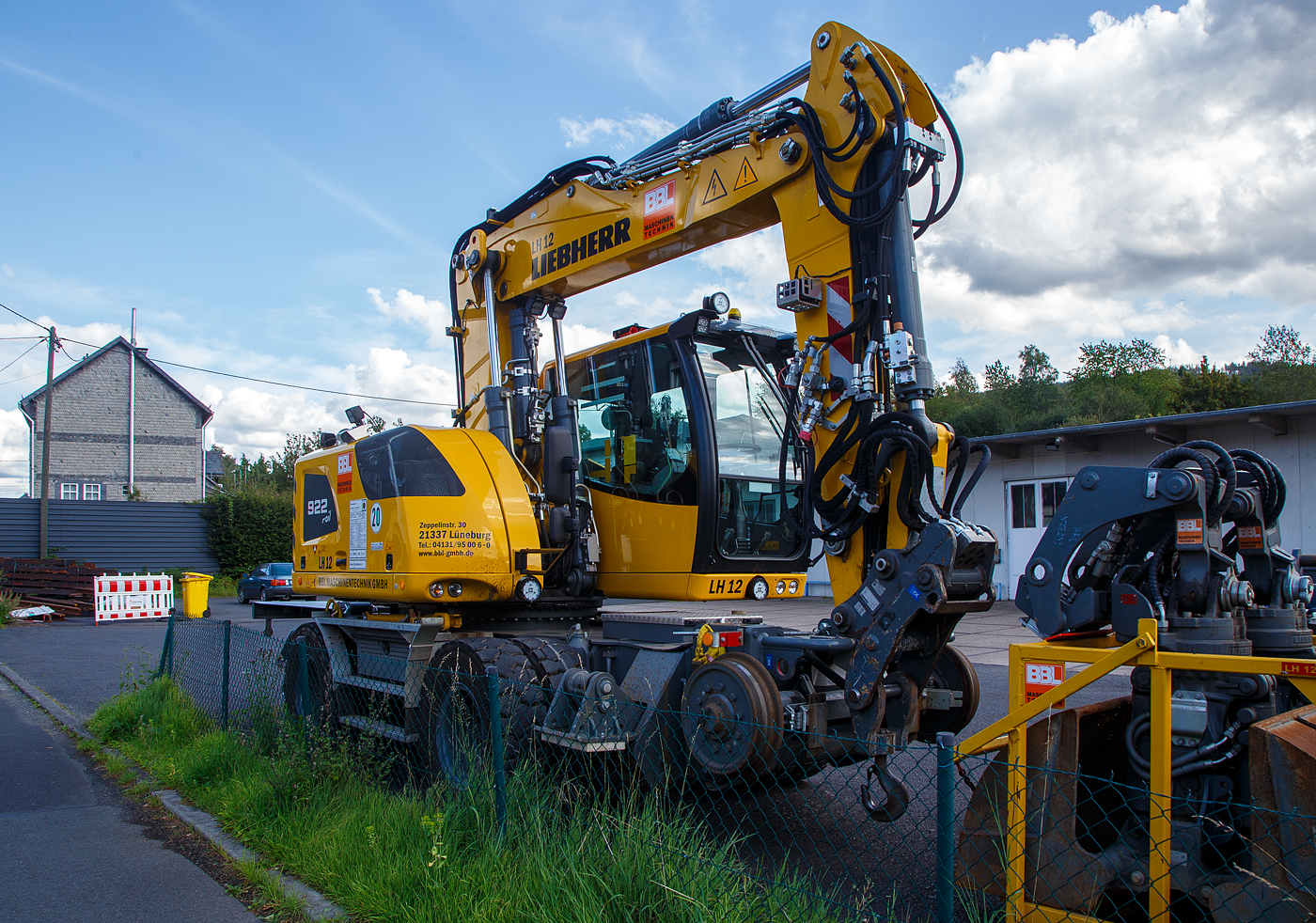 Liebherr Zweiwegebagger A 922 Rail Litronic (Baureihe 1190) mit Abstützpratzen, interne Nr. LH 12 der BBL Maschinentechnik GmbH (Lüneburg), eigestellt durch die SES Aus- und Fortbildung e.K. (Horst / Holstein) unter der Kleinwagen Nr. D-SESAF 99 80 9904 303-1, abgestellt am 26.08.2023 in Herdorf (Ostweg) beim Lokschuppen der KSW, Betriebsstätte FGE -Freien Grunder Eisenbahn.

Der ZW-Bagger wurde 2022 von Liebherr unter der Fabriknummer KLHZ1509JZK137327 gebaut.

Der A 922 Rail Litronic kann als Zweiwegemaschine wahlweise auf der Straße oder auf Eisenbahnschienen eingesetzt werden. An beiden Seiten des Unterwagens ist das Schienenfahrwerk angebracht. Während des Aufgleisens bringt das Schienenfahrwerk die Bereifung auf Schienenniveau, wobei die inneren Räder der Zwillingsbereifung den Fahrantrieb auf der Schiene übernehmen.

TECHNISCHE DATEN:
Spurweite: 1.435 mm
Länge über Puffer: 6.400 mm
Achsabstand (Schiene): 5.700 mm
Laufraddurchmesser (Schiene): 500 mm (neu)
Eigengewicht: 24 t
Motorbauart: wassergekühlter 4Takt - 4-Zylinder-Reihendieselmotor mit Common-Rail-Einspritzsystem, Turbolader und Ladeluftkühlung
Motortyp: Liebherr D924 – FPT 
Motorhubraum: 4,5 Liter
Motorleistung: 120 kW / 163 PS
Höchstgeschwindigkeit (Hg): 19,9 km/h (in Kreuzungen und Weichen 10 km/h)
Zugkraft: 117 kN
Bremse: Kfz.-/SFE-Bremse und Wagonbremsanlage
Zul. Anhängelast: 120 t (ungebremst 40 t)
Zur Mitfahrt zugel. Personenzahl: 1 (und Fahrer)
Antrieb auf Schiene: Über Reibantrieb der Straßenreifen
Hinterer Schwenkradius: 2.000 mm
Max. Neigung: 40 ‰
Max. Gleisüberhöhung: 200 mm
