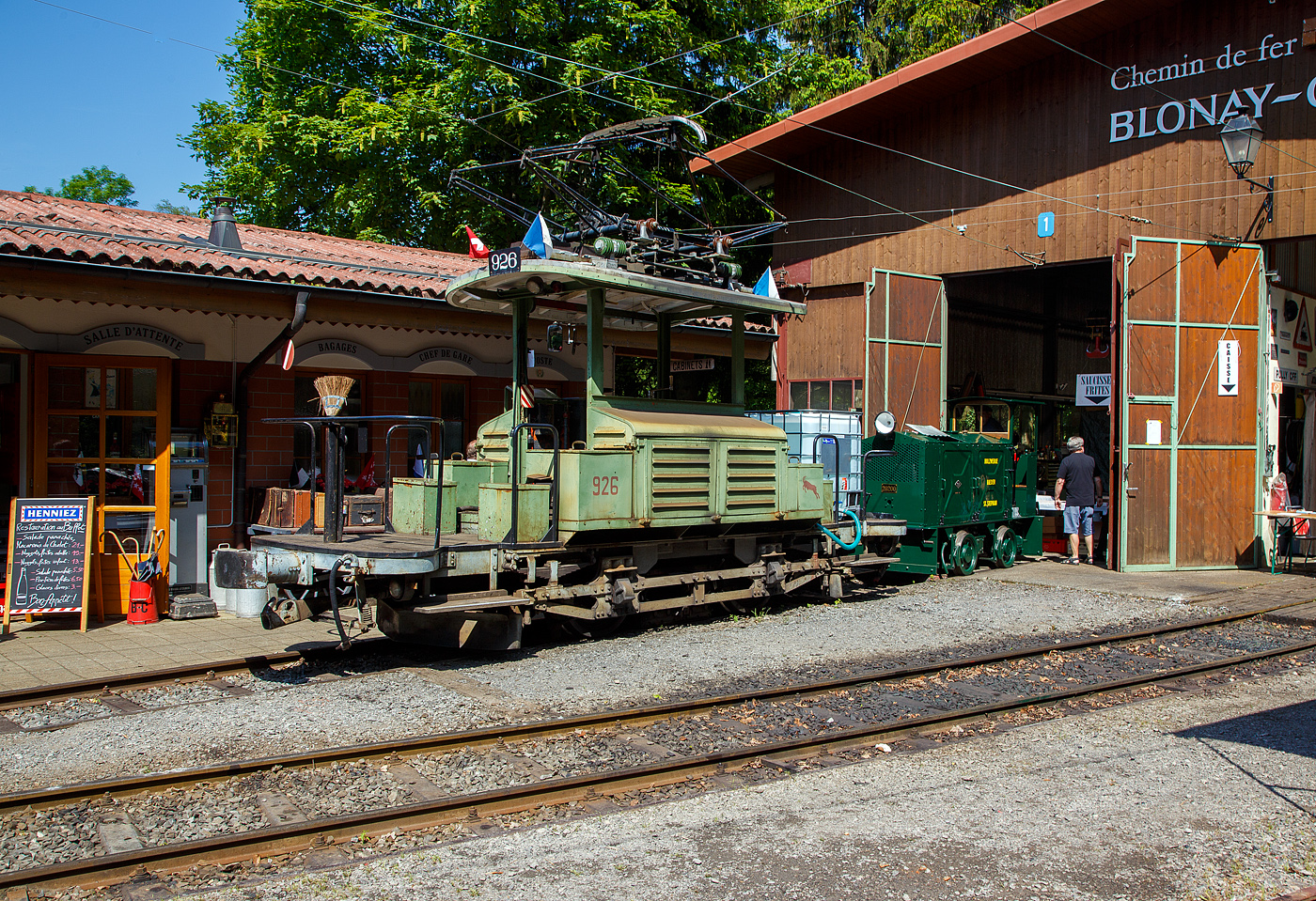 Mit einem 1m�-Wassertank und einer Motorspritze ausgestatte, als L�schzug, der Te 2/2 926 der Museumsbahn Blonay-Chamby, ex VBZ (Verkehrsbetriebe Z�rich) Schienentraktor Xe 2/2 – 1926, ex Xe 2/2 – 926, ex StStZ Xe 2/2 – 926, der Museumsbahn Blonay-Chamby am 27.05.2023 im Museum Chaulin. Dahinter der kleine ex MOB Schienentraktor Tm 2/2 Nr. 1, ex Holzwerk Rieder, der Museumsbahn.

Der Te 2/2 Schienentraktor wurde 1935 von der damaligen St�dtische Stra�enbahn Z�rich (StStZ) selbst gebaut, der elektrische Teil ist von der Maschinenfabrik Oerlikon (MFO). Gebaut worden sind, zwische1930 und 1935, drei dieser Rangiermaschinen Nr. 924-926 (ab 1946 in Nr. 1924 bis1926), dabei wurden Untergestell, Elektrik und Motoren von Ce 2/2 Triebwagen der Serie 57-84 (mit markantem Peckham-Untergestell) verwendet. 

Die drei Man�vrierwagen von erhielten zur Erleichterung der Fahrtrichtungswechsel von Anfang an einen Pantografen statt des umst�ndlichen Lyrab�gels. Die Rangierer f�gten in den Depots den Triebwagen f�r die Hauptverkehrszeit die Beiwagen zu. Die F�hrerst�nde waren l�ngs eingebaut, mit freier Sicht auf die Kupplungen, so konnte man mit ihnen sozusagen millimetergenau anfahren. Ihr gr�ner Anstrich und das charakteristische Fahrverhalten trugen ihnen den Spitznamen „Laubfrosch“ ein.

Speziell f�r Z�rich war die gro�e Flotte von Rangierfahrzeugen. Diese hatten die Aufgabe, f�r die Sto�zeit Verst�rkungswagen beizustellen und danach wieder von den Tramz�gen abzuziehen. Dazu geh�rten auch Fahrten zwischen dem zugeteilten Depot und den Bereitstellungsgleisen an Wendeschleifen. Ende der 1960ziger Jahre wurde, durch die gro�e Zahl angeschafften Mirage-Gelenkz�ge, die Flotte von 24 St�ck Rangierfahrzeugen �berfl�ssig. Das Beistellen und Abziehen von Tramanh�ngern vor und nach der Sto�zeit war nun �berfl�ssig. So war 1969 war ihre Zeit abgelaufen. W�hrend die beiden Xe 2/2 1924 und 1025 St�ck abgebrochen wurden, �bergab die Stadt Z�rich Xe 2/2 1926 an die eben im Aufbau begriffene Museumsbahn Blonay - Chamby BC. Dort leistete das gut unterhaltene und sehr bewegliche Triebfahrzeug wertvolle Dienste bei der Wiederinbetriebnahme der Strecke und beim Bau des Depots. Heute wird der „Laubfrosch“ mit seiner alten Z�rcher Nummer 926 bestimmungsgem�� als Rangierfahrzeug auf dem Depotareal der BC benutzt. Hier kann der Laubfrosch seine St�rken ausspielen. F�r den Einsatz auf der Museumsbahn musste Xe 2/2 926 die +GF+-Kupplung gegen eine herk�mmliche Mittelpufferkupplung tauschen. Um den Betrieb unter der Spannung von 1000 V DB (MOB-GFM) zu erm�glichen, wurde ein zus�tzlicher Widerstand montiert, die Stra�enbahn Z�rich fuhrt ja unter 700 V DC. Trotz der zus�tzlichen Widerst�nde leistet er sehr gute Arbeitet bei der BC. Bei der Museumsbahn Blonay–Chamby t�gt der Te 926 nicht den Spitznamen „Laubfrosch“ sondern „Le Bouc“ (Der Bock).

Hier wurde das Fahrzeug pr�ventiv als L�schfahrzeug, f�r evtl. Bek�mpfung von B�schungsbr�nden nach Funkenwurf durch die Dampflokomotive, vorgehalten. Gelegentlich r�ckt die BC Xe 2/2 926 mit dem Sprengwagen Xe 2/2 1, ex Stra�enbahn Biel aus, der noch nicht wieder mit Fahrmotoren ausger�stet ist.

TECHNISCHE DATEN:
Spurweite: 1.000 mm (Meterspur)
Gewicht: 9,3 t
H�chstgeschwindigkeit: 36 Km/h
Leistung: 2 x 44 kW = 88 kW (120 PS)
Triebraddurchmesser: 840 mm (neu)
Getriebe�bersetzung: 1:4,277
Spannung: (urspr�nglich) 700 V DC, bei der BC 1000 V DC

Quellen: BC, Drehscheibe
