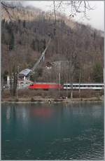 Während das Tresse der Harderbahn steil bergauf führt, hat eine SBB Re 460 mit eine IC/IR gerade den Bahnhof von Interlaken Ost verlassen und fährt nun der Aare entlang in Richtung