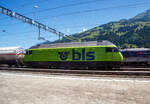 In Frutigen vor dem Lötschberg-Basistunnel wartet am 11 Juli 2022 die BLS Re 465 005, ex „Niesen“ (91 85 4465 005-7 CH-BLS) mit einem Kesselwagenzug auf Weiterfahrt, so konnte ich sie aus einem Zug aufnehmen.

Die Lok wurde 1994 von der SLM (Schweizerische Lokomotiv- und Maschinenfabrik) in Winterthur unter der Fabriknummer 5642 gebaut, der elektrische Teil ist von der ABB (Asea Brown Boveri).

Die Re 465 ist eine von der BLS Lötschbergbahn beschaffte elektrische, vierachsige Universallokomotive mit Umrichtertechnik. Sie ist eine Weiterentwicklung der Re 460 der SBB und gehört zur Lok-2000-Familie. Nach der Erstbestellung der BLS über acht Maschinen die 1994 gebaut wurden, folgten weitere 1997 zehn Loks (009–018) für den Huckepackkorridor. Diese Loks aus den 90er-Jahren sind für den Personen- wie für den Güterverkehr im Einsatz. Künftig werden sie auch beim Autoverlad und im Berner Oberland eingesetzt, nicht mehr im originalen Dunkelblau, sondern im leuchtenden BLS-Grün.

Die Re 465 stellen eine Weiterentwicklung der Re 460 dar. Wie diese hat sie GTO-Thyristoren als Ventile im Stromrichter und Drehstrom-Asynchronmotoren. Der Unterschied liegt in der Umrichteranlage. Im Fall der Re 460 besteht ein Traktionsstromrichter (in der Lok sind zwei Geräte verbaut, ein Gerät pro Drehgestell) aus zwei Vierquadrantenstellern, die den Zwischenkreis parallel versorgen, und einem Motor-Wechselrichter, der zwei Motoren parallel speist. Die Stromrichter der Re 465 gruppieren sich zu drei Vierquadrantenstellern parallel an einem Zwischenkreis mit zwei Wechselrichtern, je einen Motor im Drehgestell speisend. Somit lässt sich eine schleudernde Achse schneller und effektiver wieder in normalen Lauf bringen. Wurde bei der Entwicklung der Re 460 auf Dreipunkt-Stromrichter gesetzt, wurde im Gegensatz dazu die Re 465 mit Zweipunkt-Technik ausgestattet. Die Zwischenkreisspannung senkte man entsprechend von 3,5 kV (Re 460) auf 2,8 kV (Re 465). Zudem besitzt die Re 465 sechspolige Asynchron-Fahrmotoren (Re 460: vierpolige Asynchronmotoren). Daraus resultiert eine gegenüber der Re 460 erhöhte Dauerleistung von 6.270 kW (Stundenleistung von 7.000 kW).

Die Radsätze im Drehgestell stellen sich radial zum Gleisbogen ein.

Zudem war die Re 465 im Unterschied zur Re 460 mit der Vielfachsteuerung des Systems IIId und (mit Übergangskabel) BLS/BBC ausgerüstet. Diese erlaubte die Vielfachsteuerung zum Beispiel mit Re 4/4II, Re 4/4III, Re 6/6, Re 425 oder Ae 415, beim Refit wurde diese Vielfachsteuerung ausgebaut und dafür eine Vielfachsteuerung für TRAXX und Vectron-Loks eingebaut. 

Zwischen 2019 und 2022 durchliefen alle 18 Loks des Typs Re 465 ein Modernisierungsprogramm (Refit). Darin enthalten waren unter anderem der Einbau der Vielfachsteuerung ZMS für den Güterverkehr mit Traxx- und Vectron-Lokomotiven und ETB (Ethernet Train Backbone) für den Autoverlad am Lötschberg. Die Vielfachsteuerung des Systems IIId wurde ausgebaut, so ist die Vielfachsteuerung mit älteren Loks wie der Re 425 nicht mehr möglich. Die Kästen wurden saniert und neu in hellem BLS-Lindengrün mit blauem Logo lackiert. 

Mit diesem Refit verlängert sich die Lebensdauer der rund 25-jährigen Loks um weitere 15 Jahre. Sie sind neu bis ins Jahr 2040 einsetzbar. Die modernisierten Lokomotiven sind gut zu erkennen, sie sind neu grün lackiert werden damit zur auffälligen und klar ersichtlichen BLS-Markenbotschafterin. Das Modernisierungsprogramm kostete insgesamt rund 20 Millionen CHF. Modernisiert wurden alle Loks in der BLS-Werkstätte Bönigen. Im Zuge des Refits wurden alle Taufnamen und Bilder entfernt.

Im Personenverkehr zieht bzw. stößt die Re 465 die GoldenPass-Express-Züge zwischen Interlaken Ost und Zweisimmen, im Güterverkehr wird sie in Mehrfachtraktion mit anderen Loks (TRAXX und Vectron) eingesetzt. Die Loks werden ab Ende 2023 auch beim Autoverlad eingesetzt und ersetzen damit die braunen Loks des Typs Re 425. Damit kann die BLS auf eine Neubeschaffung verzichten.

TECHNISCHE DATEN:
Spurweite: 1.435 mm (Normalspur)
Achsformel: Bo’Bo’
Länge über Puffer: 18.500 mm
Drehzapfenabstand:11.000 mm
Achsstand im Drehgestell: 2.800 mm
Treibraddurchmesser: 1.100 mm (neu)
Höhe: 4.540 mm
Breite: 3.000 mm
Dienstmasse: 84 t
Höchstgeschwindigkeit: 230 km/h
Stundenleistung: 7.000 kW
Dauerleistung: 6.400 kW
Anfahrzugkraft: 300 kN
Stromsystem: Wechselstrom 15 kV 16,7 Hz

Quellen: BLS, Wikipedia und Anschriften
Stand/Überarbeitung: Oktober 2025