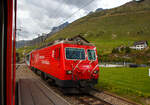 Wir sind am 07 September 2021 mit dem MGB Regionalzug von Andermatt nach Visp (auf der Furka-Oberalp-Bahn) unterwegs, in m�ssen wir Hospental (von lateinisch hospitale „Herberge“)  den Gegenzug abwarten. So kommt uns die MGB HGe 4/4 II 103 „Chur / Marcau da Cuera“ mit dem Glacier Express (Zug PE 902) entgegen.

Die HGe 4/4 II 103 „Chur / Marcau da Cuera“  wurde 1986 von der SLM (Schweizerische Lokomotiv- und Maschinenfabrik) in Winterthur unter der Fabriknummer 5292 gebaut und an die FO (Furka-Oberalp-Bahn) geliefert. Der elektrische Teil ist von BBC. Sie ist eine der 5 Prototypen Maschinen.

Die HGe 4/4 II ist eine schmalspurige (1.000 mm) gemischte Zahnrad- und Adh�sions-Lokomotive. Eine erste Serie von f�nf Lokomotiven wurde gemeinsam von der Furka-Oberalp-Bahn (FO) sowie von der SBB f�r die Br�nigbahn, die heute zur Zentralbahn (zb) geh�rt, beschafft. Da sich dieser Lokomotivtyp bew�hrte, wurden weitere elf Lokomotiven bestellt, und schlie�lich gab auch noch die Brig-Visp-Zermatt-Bahn (BVZ) f�nf Loks in Auftrag.

Die HGe 4/4 II bespannt vor allem schwere Personenz�ge, zum Teil im Pendelzugbetrieb. Bei der Zentralbahn bespannte sie bis 2012 alle Schnellz�ge von Meiringen nach Luzern, bei der Matterhorn Gotthard Bahn die Z�ge des Glacier-Express. Weiter f�hren die Loks Pendelz�ge Brig–Visp–Zermatt und seit der Er�ffnung des Tunnels nach Engelberg Pendelz�ge Luzern–Engelberg. Au�erdem werden aushilfsweise Autopendelz�ge durch den Furkatunnel gef�hrt. Schlie�lich geh�ren neben weiteren Personenz�gen auch diverse G�terz�ge Visp–Zermatt sowie bis 2013 Disentis–Sedrun (NEAT-Baustelle) zum Aufgabengebiet.

Konstruktion:
Der Lokomotivkasten ist ein Stahlblechkasten mit gesickten Seitenw�nden. Die asymmetrische Frontscheibe aus beheizbarem Verbundglas verbessert die Sicht f�r den Lokomotivf�hrer. Die drei Dachelemente sind aus Aluminium. Die Pufferkr�fte werden �ber Verstrebungen auf den ganzen Kasten �bertragen, weshalb auf seitliche Maschinenraum�ffnungen verzichtet werden musste. Der gesamte Kasten hat ein Gesamtgewicht von nur 5,9 Tonnen. Er kann ohne bleibende Deformation eine zentrale Druckkraft von 1000 kN aufnehmen.

Die Drehgestelle sind als geschwei�te Hohltr�gerkonstruktion mit zwei L�ngstr�gern und einem kr�ftigen mittleren Quertr�ger sowie zwei Kopftraversen ausgef�hrt. Sie haben einen Achsstand von 2980 mm, und die Flexicoil-Federn st�tzen den Kasten auf die seitlich an die L�ngstr�ger angeschwei�ten Federwannen. Die Zug- und Druckkr�fte werden durch seitlich angeordnete Stangen mit Sph�rolastiklagern �bertragen. Wegen des kurzen Achsstands sind die Fahrmotoren oberhalb des Drehgestellrahmens angebracht.
F�r den Antrieb wurde erstmals der Differentialantrieb eingebaut, der es erm�glicht, im Zahnstangenbetrieb auch einen Anteil der Zugkraft �ber den Adh�sionsantrieb aufzubringen. Dies setzt wiederum eine Schlupfbegrenzung im Differentialgetriebe voraus, um ein Schleudern oder Gleiten der R�der zu verhindern. Da die zweilamellige Abtzahnstange (System Abt) der FO nicht die gesamte Zugkraft aufnehmen kann, ist die Mithilfe des Adh�sionsantriebs notwendig; dieser �bernimmt einen Drittel der Zugkraft. H�tte sich der Antrieb nicht bew�hrt, w�re es zumindest am Br�nig mit der Riggenbachzahnstange m�glich gewesen, auf einen abkuppelbaren Adh�sionsantrieb zu wechseln. Dies war aber nicht notwendig, da das Differentialgetriebe zur vollen Zufriedenheit funktionierte.

Bremssysteme:
Dank der elektrischen Rekuperationsbremse ist eine gleichm��ige Beharrungsbremse bei der Talfahrt m�glich.
Daneben ist eine normale automatische Druckluftbremse eingebaut, welche auch als Bremssystem I bezeichnet und im Regelbetrieb zum Halten des Zuges verwendet wird. Sie ist als Klotzbremse ausgef�hrt.
Weiterhin ist noch das Bremssystem II installiert, welches f�r Zahnradbahnen vorgeschrieben ist und es erm�glichen soll, den Zug nur mit Hilfe der Lokomotive im Zahnstangenabschnitt zum Halten zu bringen, wenn das erste Bremssystem ausfallen sollte. Dieses ist als federspeichergest�tztes Bandbremssystem ausgelegt, welches direkt auf das Zahnrad wirkt. Bei Einsatz dieser Bremse treten enorme Kr�fte auf, welche nur unter Kontrolle sind, wenn die Anh�ngelast bei der Talfahrt nicht zu gro� ist.
Schlie�lich ist eine direkt wirkende Rangierbremse vorhanden, die sich der Bremskl�tze des Bremssystems I bedient.
Die Lokomotive hat keine Handbremse, sondern wird mit Federspeicherbremsen gesichert.

TECHNISCHE DATEN der HGe 4/4 II der FO und BVZ (heute MGB), 
die Daten der  zb (Zentralbahn), ex SBB Br�nigbahn weichen ab:
Spurweite: 1.000 mm
Achsformel: Bo'Bo'
Dienstgewicht: 64 t 
Achslast: 16 t
L�nge �ber Puffer: 14'.776 mm 
H�chstgeschwindigkeit Adh�sion: 100 km/h
H�chstgeschwindigkeit Zahnrad: 40 km/h
Stromsystem: 11 kV 16.7 Hz
Anzahl der Motoren: 4
Adh�sions-Antrieb: Gelenkwelle
Antrieb Zahnrad: Differentialantrieb
Zahnradsystem:  Abt (zweilamellig)
Stundenleistung: 1.932 kW
Dauerleistung: 1.875 kW
Anfahrzugkraft: 230 kN (Adh�sion) / 280 kN (Zahnrad)
Anzahl Bremssysteme: 4
Bremsen: Rekuperation, Klotz, Federspeicher, Bandbremse
Anh�ngelast: 130 t (125 ‰)