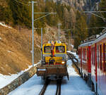 Bei Cadera überholt unser RhB Regionalzug nach St. Moritz am 20 Februar 2017 den RhB Tm 2/2 98 mit dem zweiachsigen Offenen Niederbordwagen Xa-t 931 13, er muss uns am Ausweichgleis abwarten.  

Der Traktor wurde 1999 von Windhoff unter der Fabriknummer 160807/2 gebaut. Der offenen Niederbordwagen, ex Xk-w 911 03, ex Kk-w 7316, ist Baujahr 1911. 

Das neue fünfstellige Nummernsystem der RhB:
9 = Dienstfahrzeuge 
3 = Fahrbahnbau 
1 = Transportwagen 
Die vierte und fünfte Stelle sind dann die Wagennummern.

TECHNISCHE DATEN Tm 2/2:
Spurweite: 1.000 mm
Achsfolge: B
Länge über Puffer: 8.790 mm
Achsabstand: 4.750 mm
Breite: 2.700 mm
Leergewicht: 22 t
Ladegewicht: 2 t
Höchstgeschwindigkeit: 60 km/h (60 km/h Schleppfahrt)
Motorbauart: 6-Zylinder-Dieselmotor
Motorleistung:  336 kW 
Anfahrzugkraft: 78 kN 
Stundenzugkraft: 30 kN bei 25 km/h
Leistungsübertragung: hydraulisch
