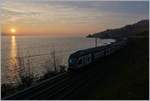 Sonnenuntergang am Genfersee; dies im Vergleiche zum BB.de Bild etwas weniger stark bearbeitete Bild zeigt nur sehr schemenaft einen SBB RABe 511 auf dem Fahrt Richtung Rivaz, und beschränkt sich