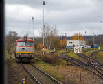 Wir erreichen am 24.11.2022 mit dem EC 360 / Ex 6 (Praha – Plzeň - Furth i.W. - Schwandorf – Regensburg – M�nchen) nun den Bahnhof Doma�lice (Taus) an der „B�hmische Westbahn“ Bahnstrecke Plzeň–Furth im Wald (S�DC 180), w�hrend rechts die ZSSK Cargo 751 173-6 als Lz �ber die Bahnstrecke Janovice nad �hlavou–Doma�lice (S�DC 185) ankommt.  

Die Kursbuchstrecke S�DC 185 von Janovice nad �hlavou nach Doma�lice (deutsch Janowitz an der Angel – Taus) ist Teil der ehemaligen B�hmisch-M�hrische Transversalbahn der ehemaligen k.k. �sterreichischen Staatsbahn (kkStB), sie verlief von der damaligen ungarischen Grenze am Vlarapass bei Uhersk� Hradi�tě (Hradisch) nach Doma�lice (Taus) und hatte dort Anschluss an bayerische Strecken.

Die ZSSK Cargo 751 173-6, ex ČSD-Baureihe T 478.1, ist eine dieselelektrische Universallokomotive der ehemaligen Tschechoslowakischen Staatsbahnen (ČSD). Die Lokomotiven pr�gten ab den 1960er Jahren den Streckendienst auf nichtelektrifizierten Strecken der ČSD und galten auf Grund ihrer Zuverl�ssigkeit als eine der erfolgreichsten Diesellokomotiven in der ehemaligen Tschechoslowakei. Unter Eisenbahnfreunden erfreuten sich die Maschinen, die auf Grund ihres markanten �u�eren den Spitznamen Bardotka (abgeleitet von Brigitte Bardot) oder Zamračen� (Finstergesicht) erhielten. Zwischen 1966 und 1977 wurden von ČKD Praha 230 Loks als T 478.1 und 82 Loks als T 478.2 gebaut.
